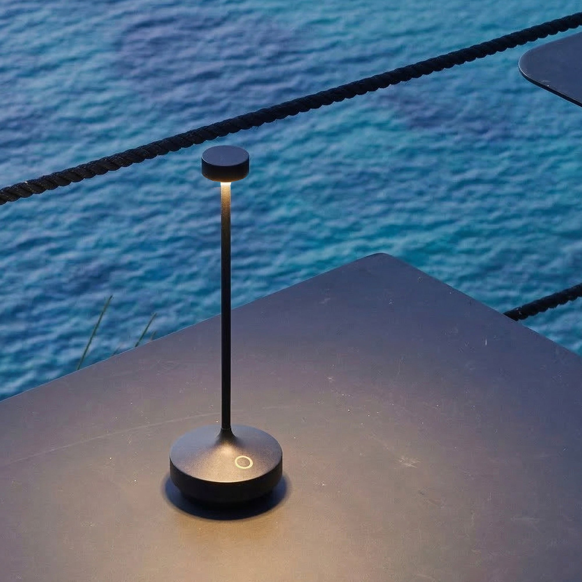 Eine moderne schwarze Lampe steht auf einem Tisch am Wasser.