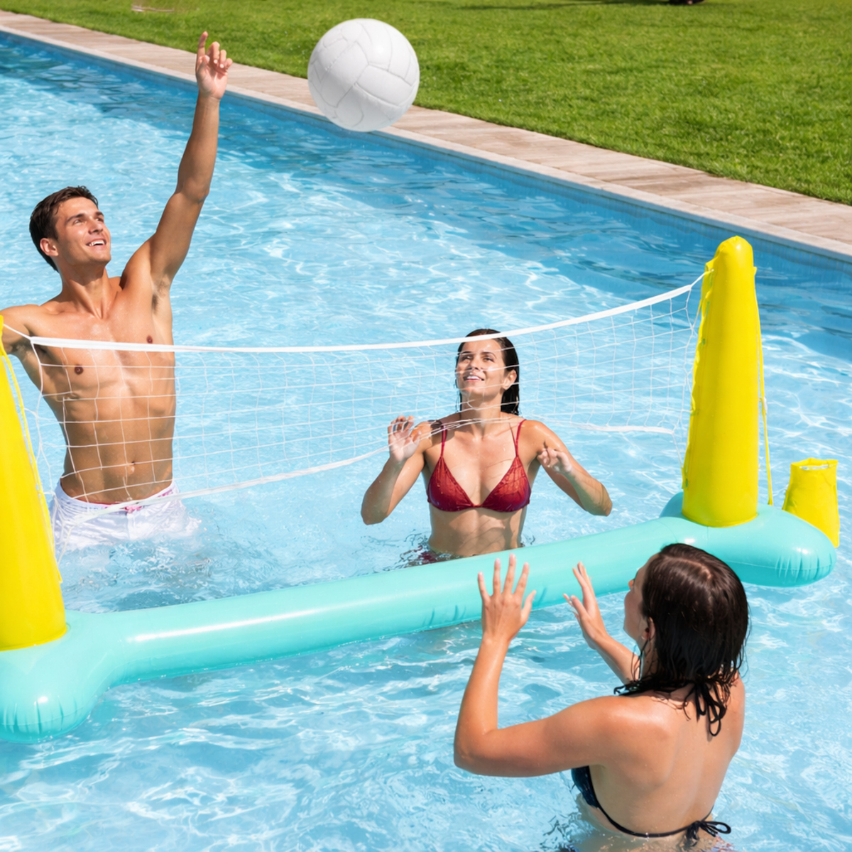 Trzy osoby grają w siatkówkę w basenie, mężczyzna uderza piłkę.