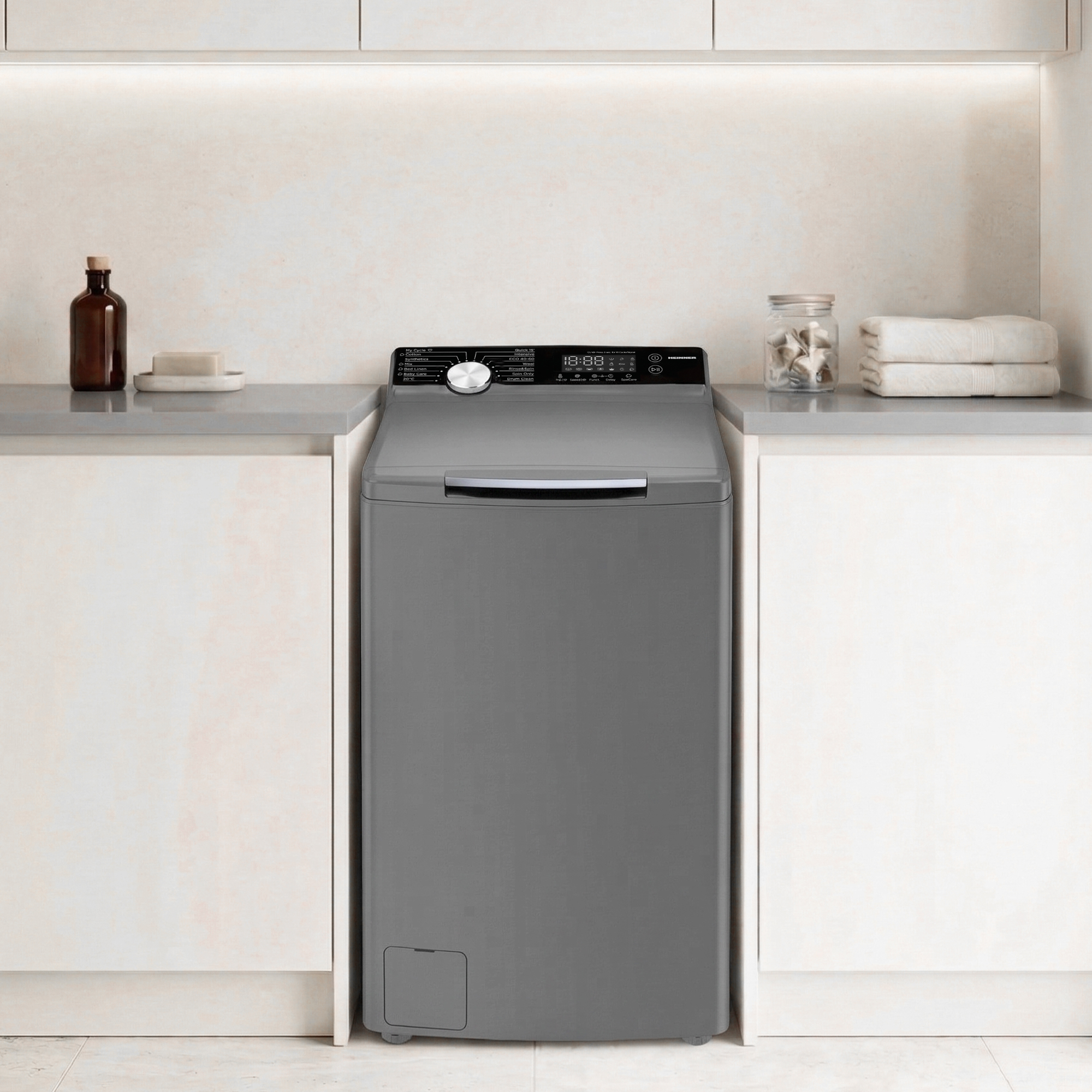 Graue Waschmaschine im Badezimmer mit Seife, Flasche, Glaskrug und Handtüchern.