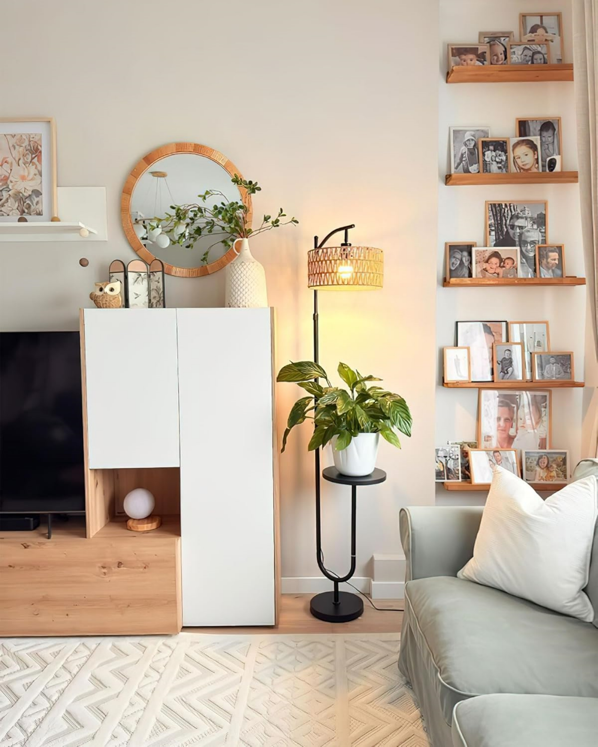 Ein Wohnzimmer mit Sofa, Regalwand voller Fotos, Lampe und pflanze.