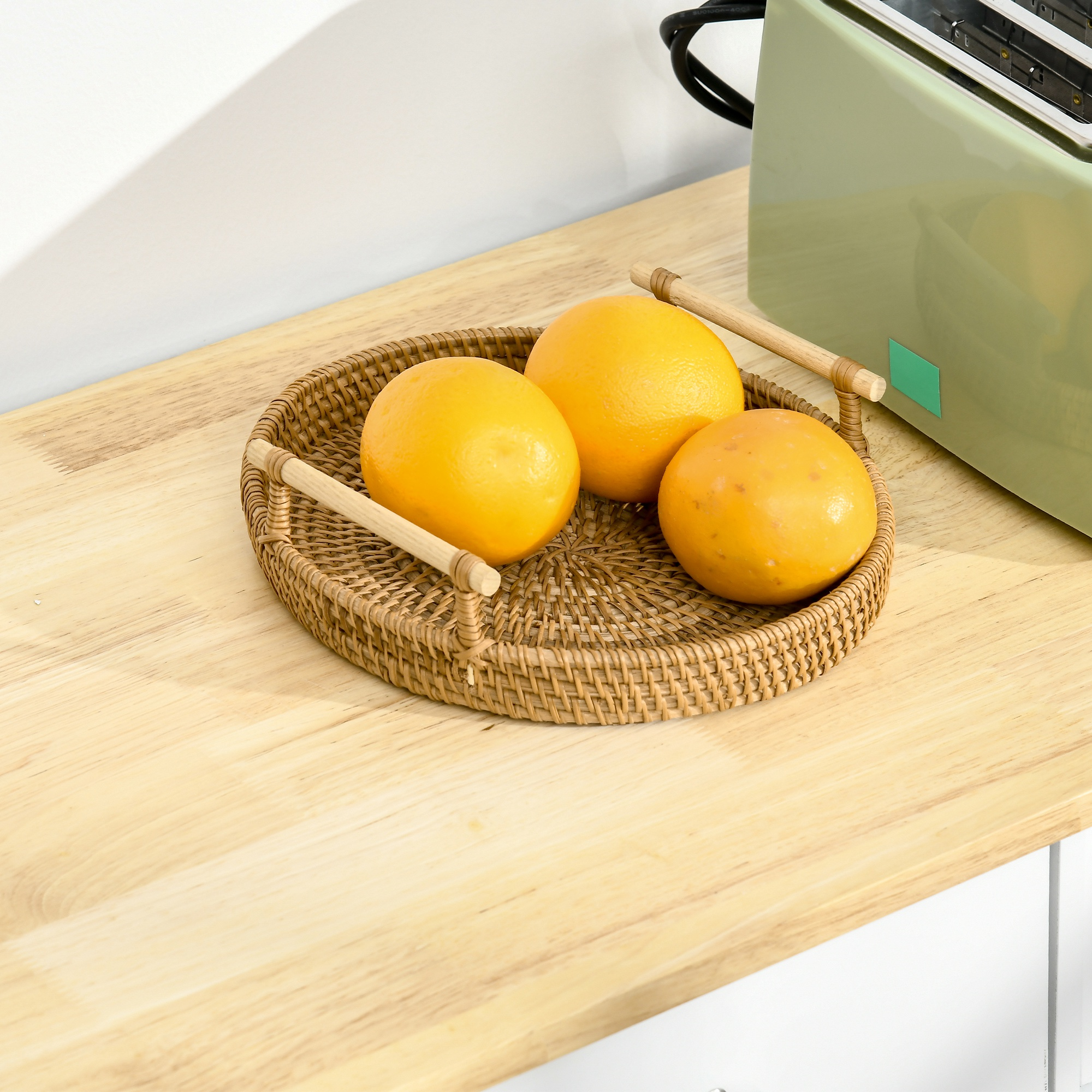 Naranjas en una bandeja tejida sobre una mesa de madera junto a una tostadora verde.