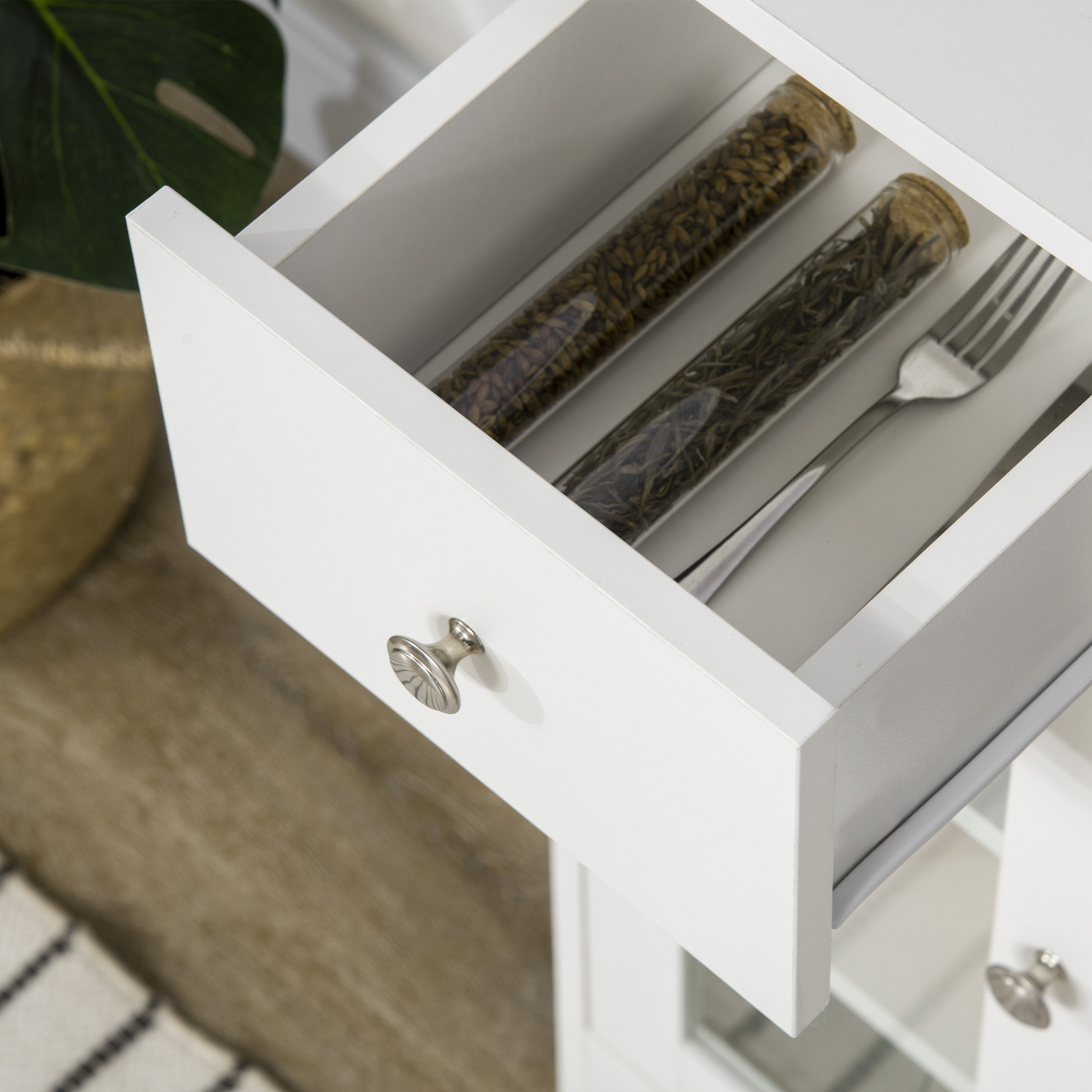 Un cajón blanco abierto con dos tubos de vidrio con hierbas y un tenedor.