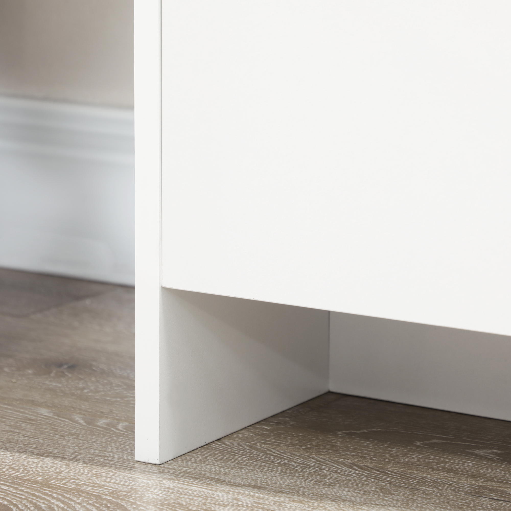 Primer plano de una esquina blanca de mueble sobre suelo de madera.