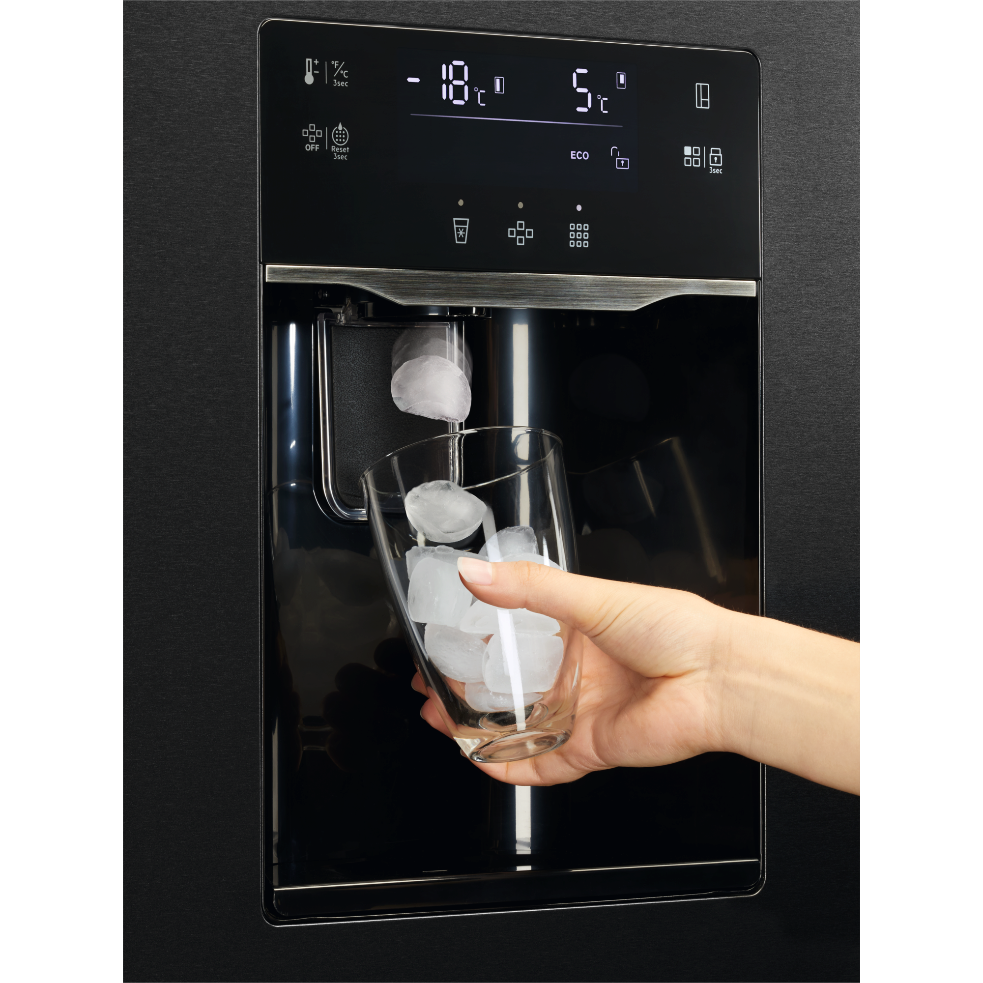 Eine Hand füllt Eiswürfel in ein Glas an einem schwarzen Kühlschrank.