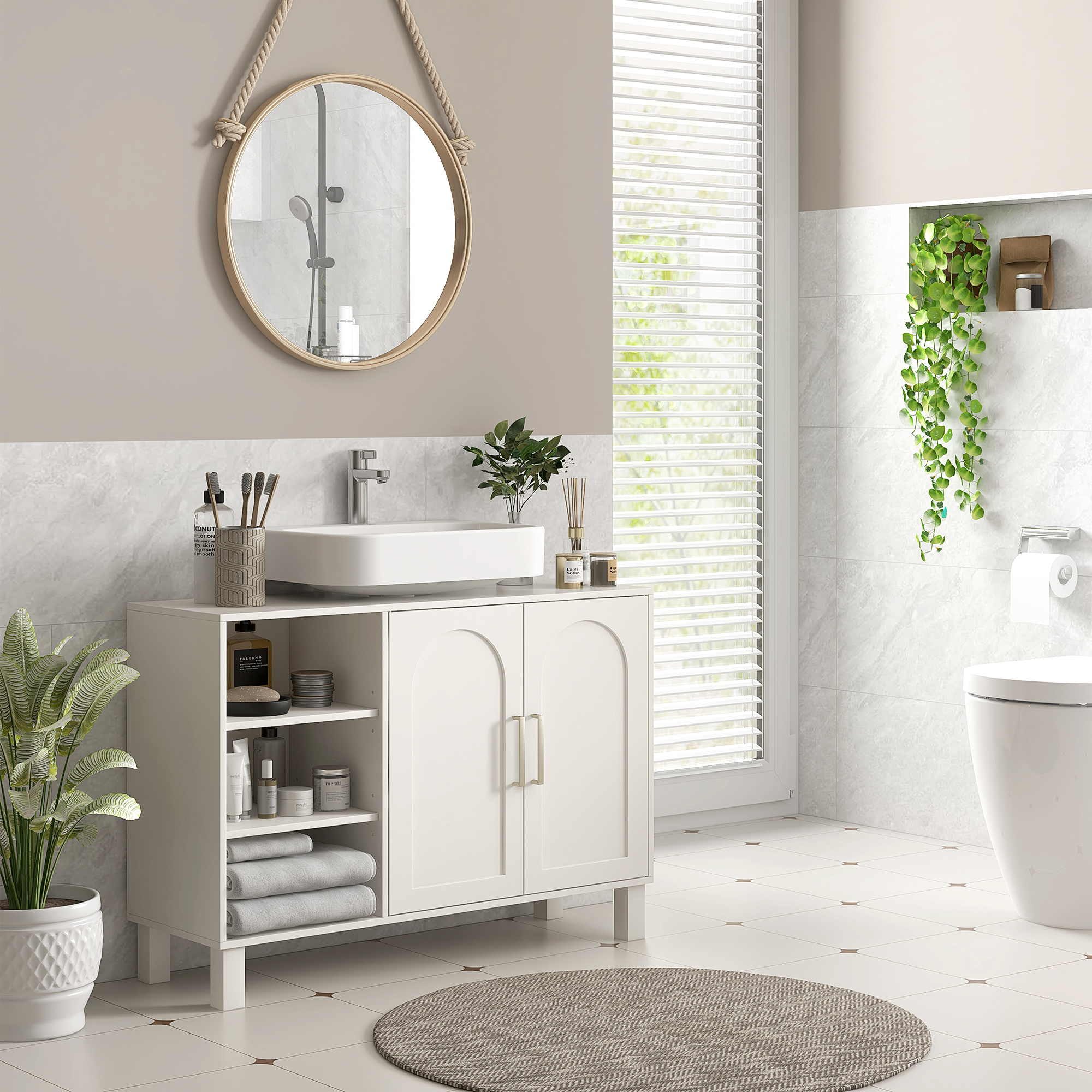 Baño moderno con mueble de lavabo blanco, espejo y váter. Plantas decoran.