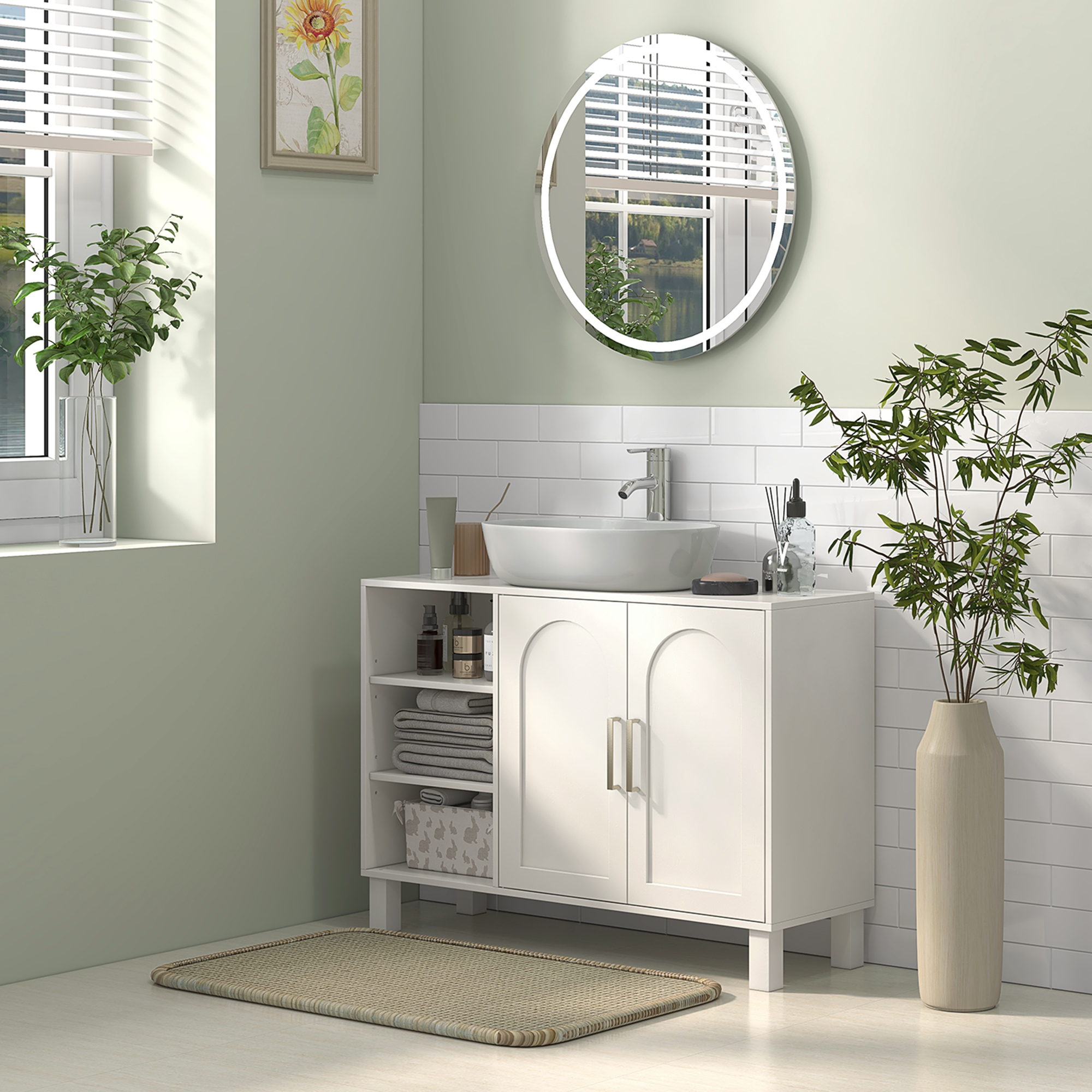 Un baño moderno con tocador blanco, espejo redondo y plantas.