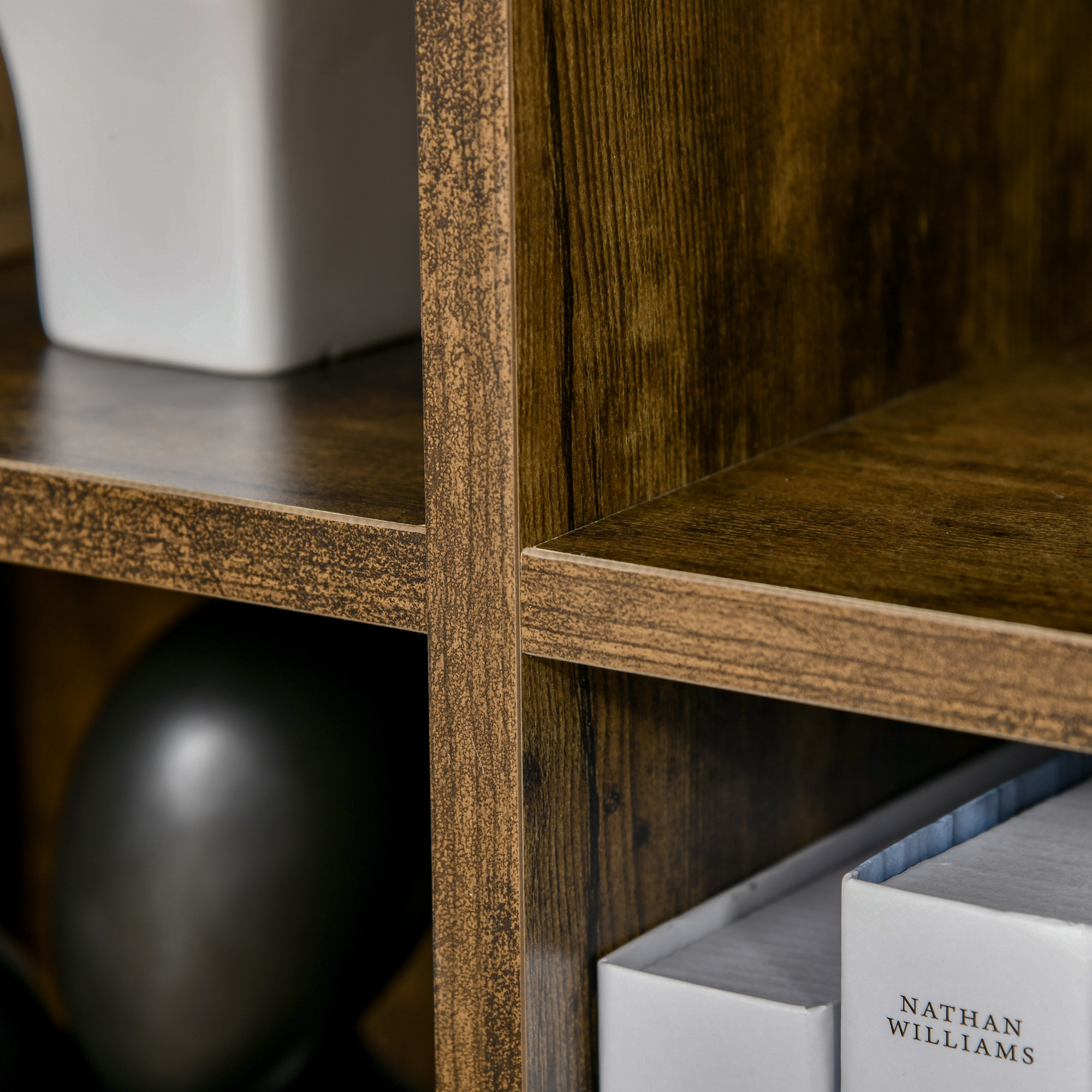 Estantería de madera con contenedor blanco, esfera negra y libros.