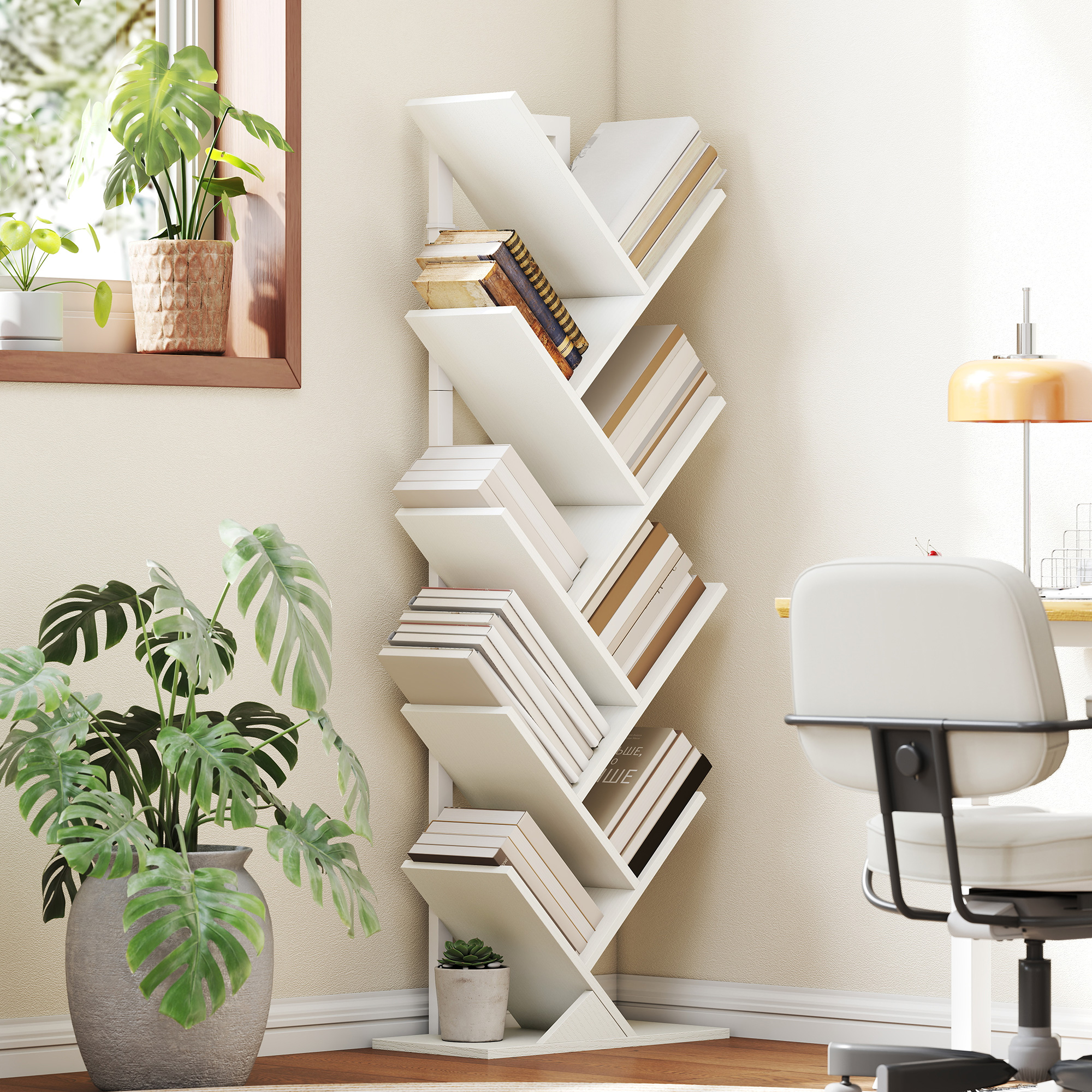 Una estantería blanca en forma de árbol con libros se encuentra junto a una ventana con plantas. Una silla y un escritorio al fondo.