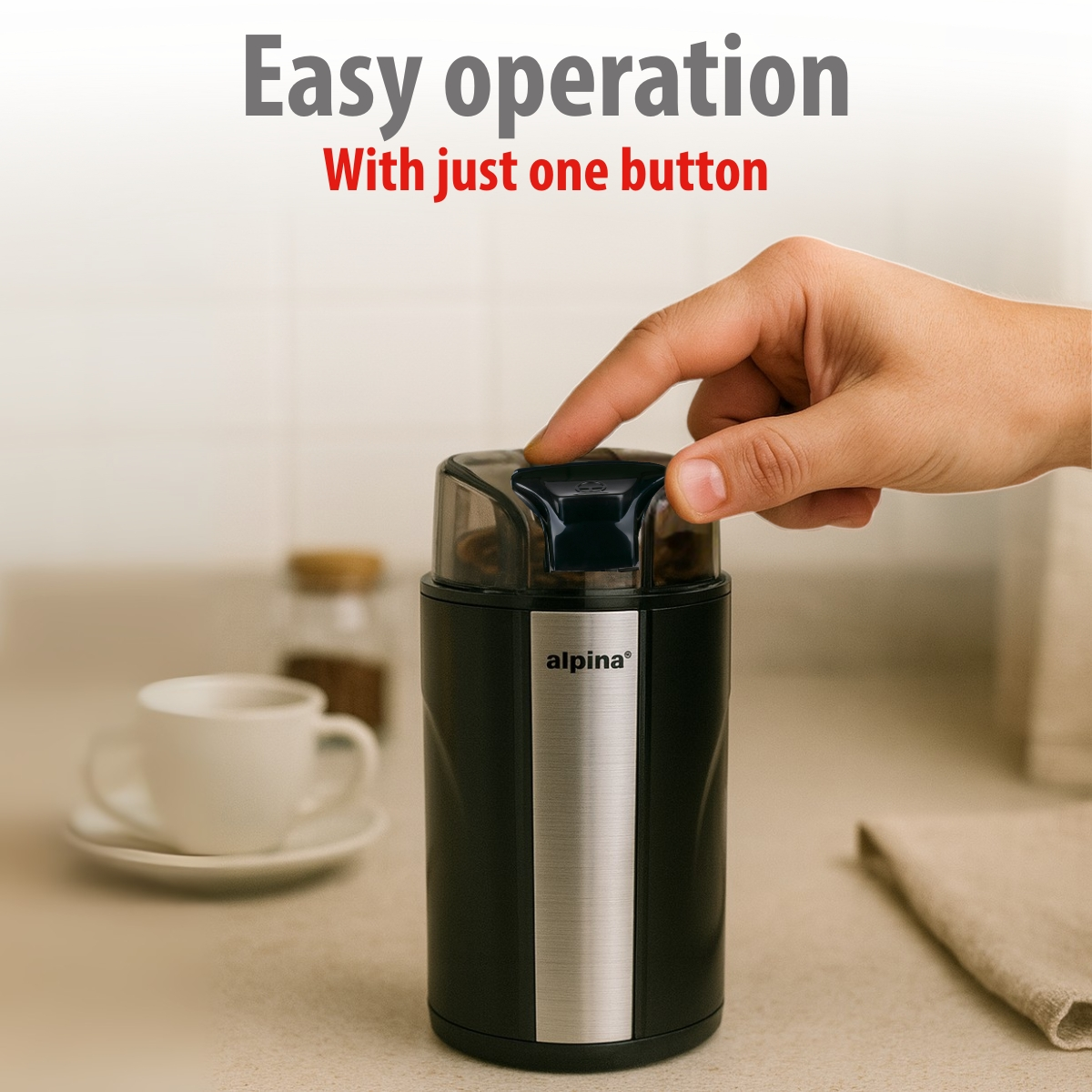 A hand presses the button of a black coffee grinder. Easy operation.