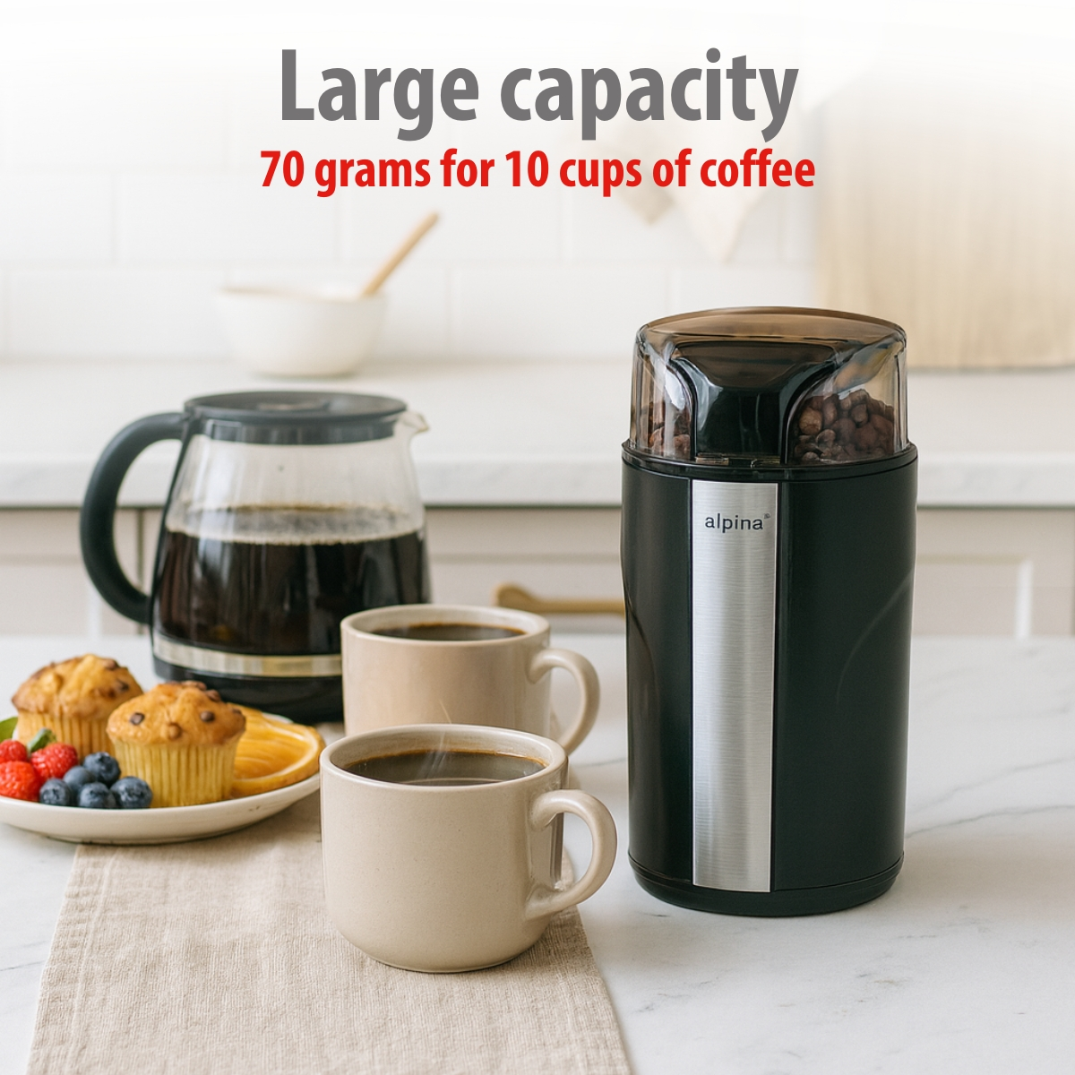 A coffee grinder with beans, a coffee pot, two cups of coffee, and pastries on a table.