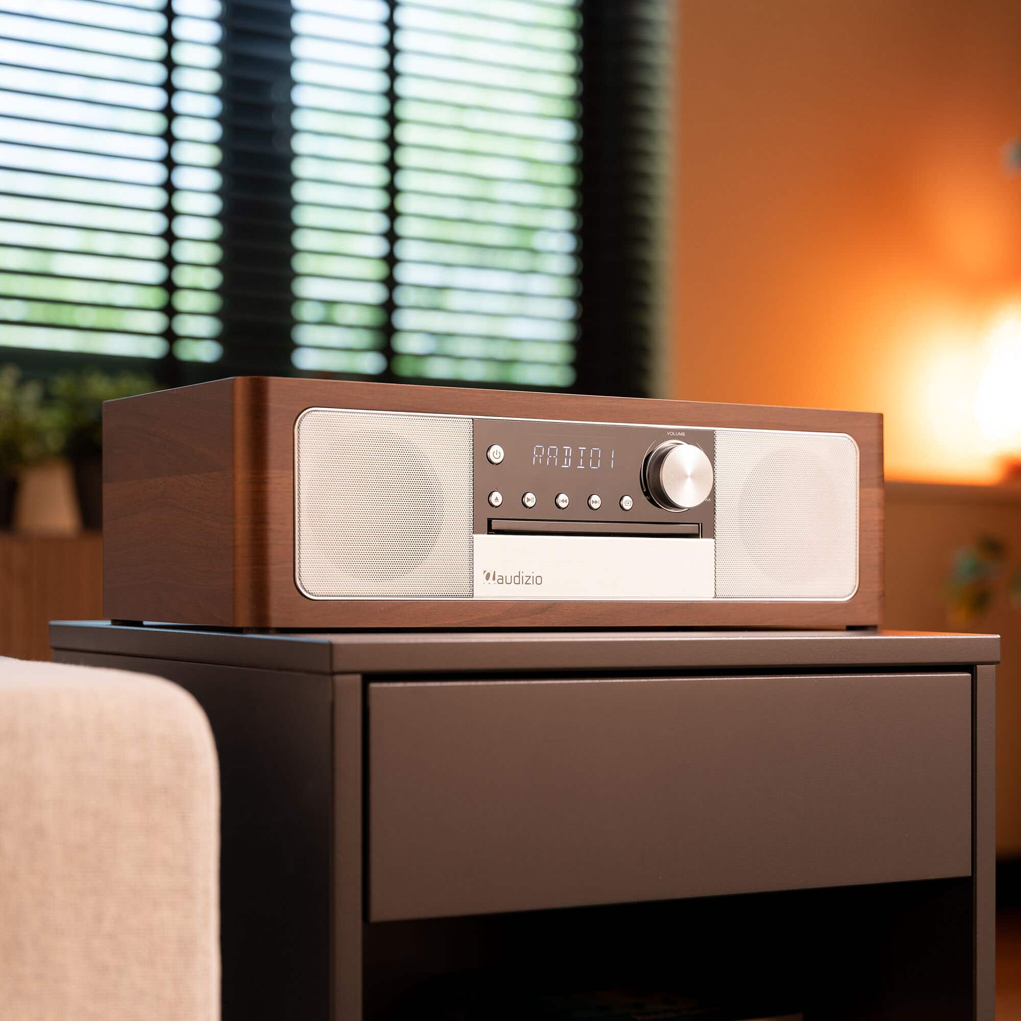 A wooden radio with silver speakers sits on a nightstand.