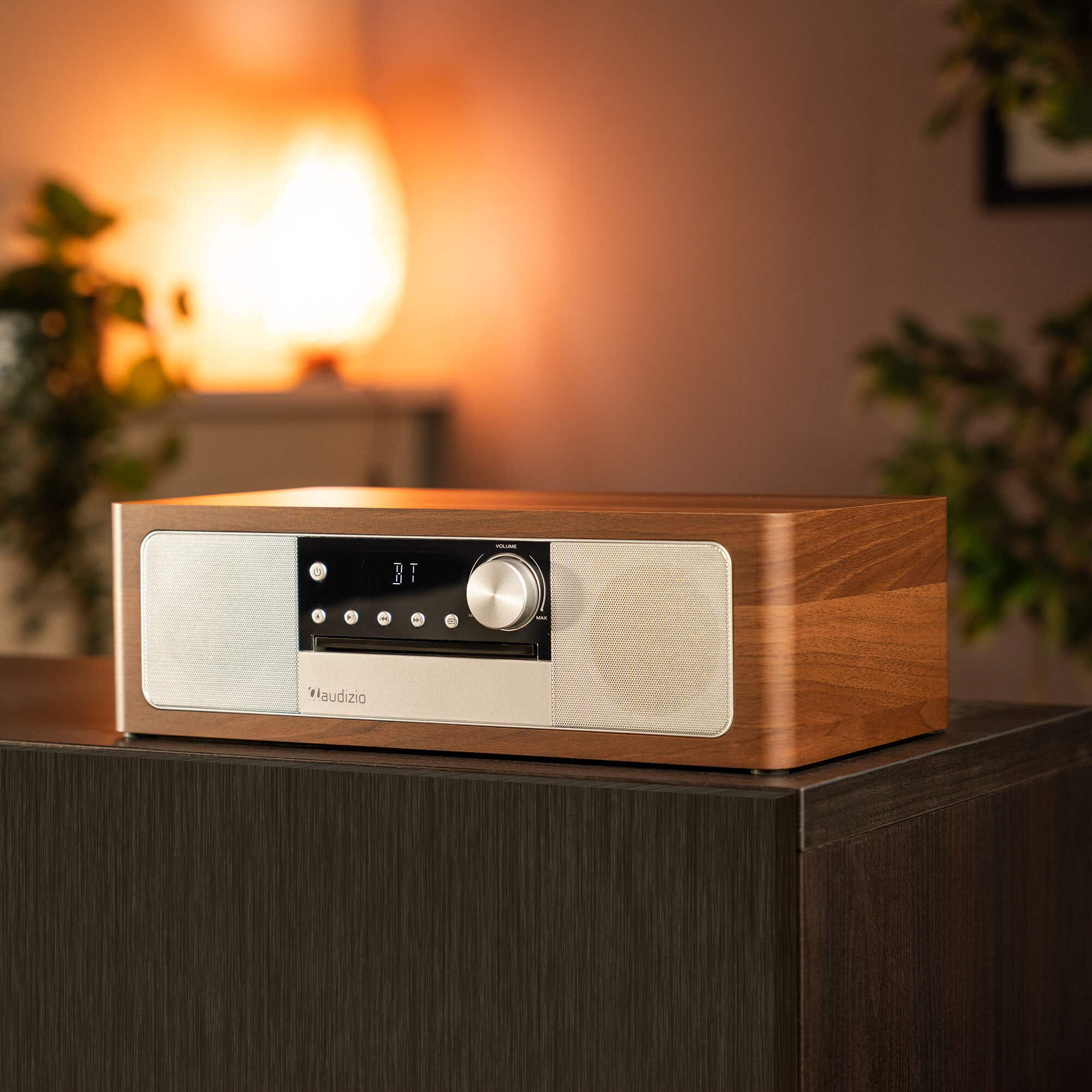 A wooden radio with CD player and speakers sits on a dark cabinet.