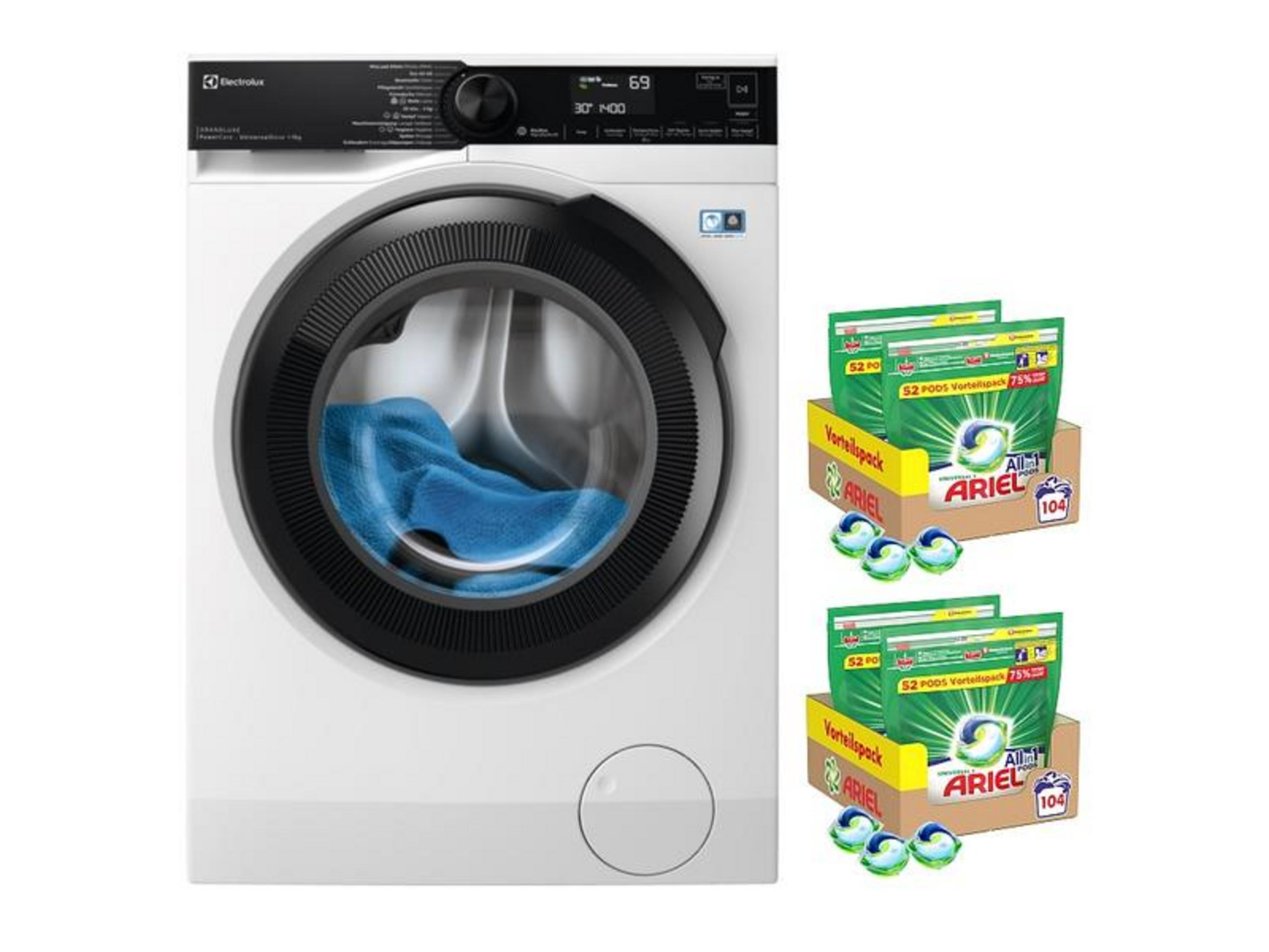 Une machine à laver blanche avec du linge bleu à l'intérieur et des paquets de dosettes Ariel à côté.