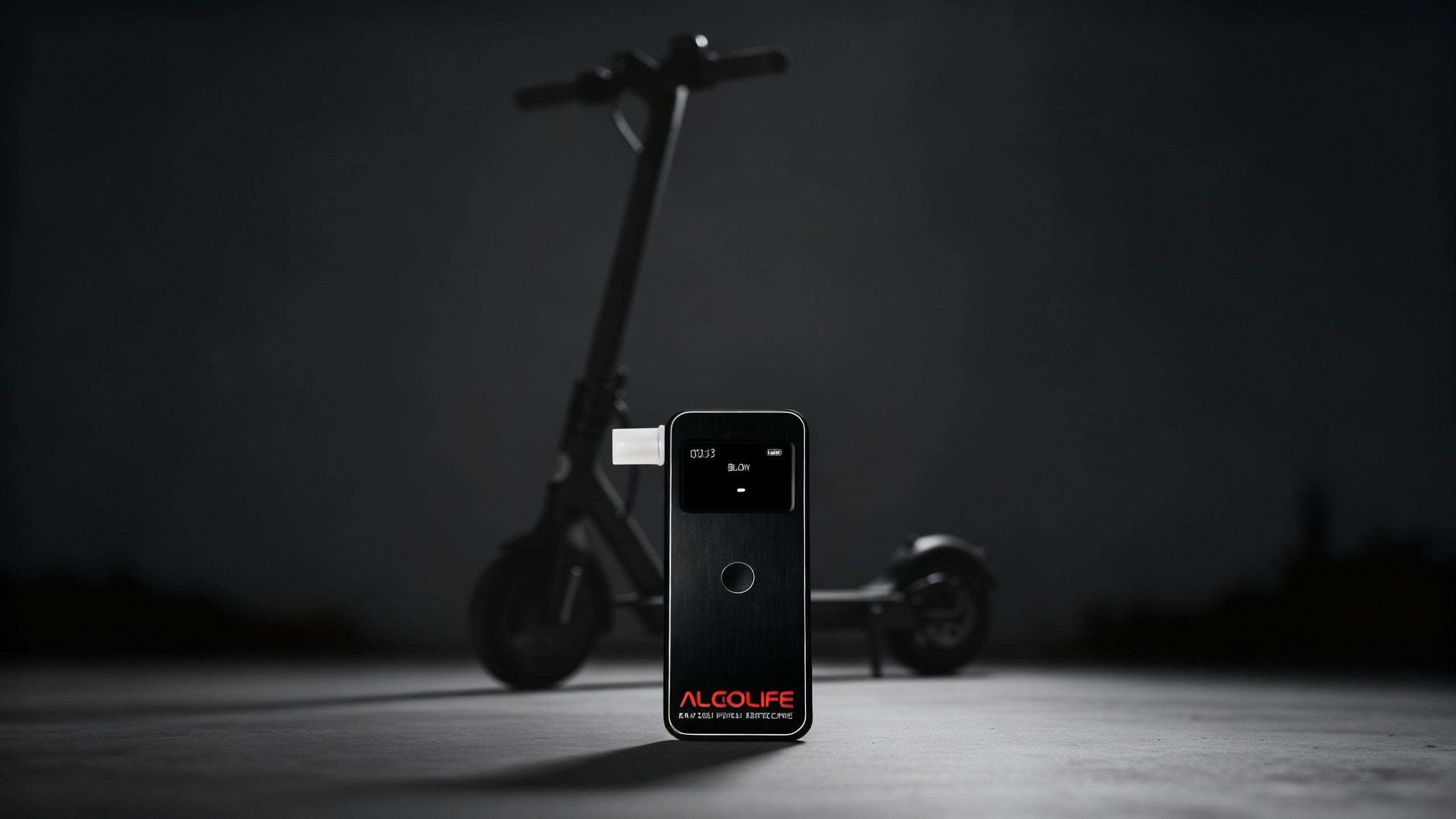 Czarny alkomat na pierwszym planie z hulajnogą elektryczną w tle.