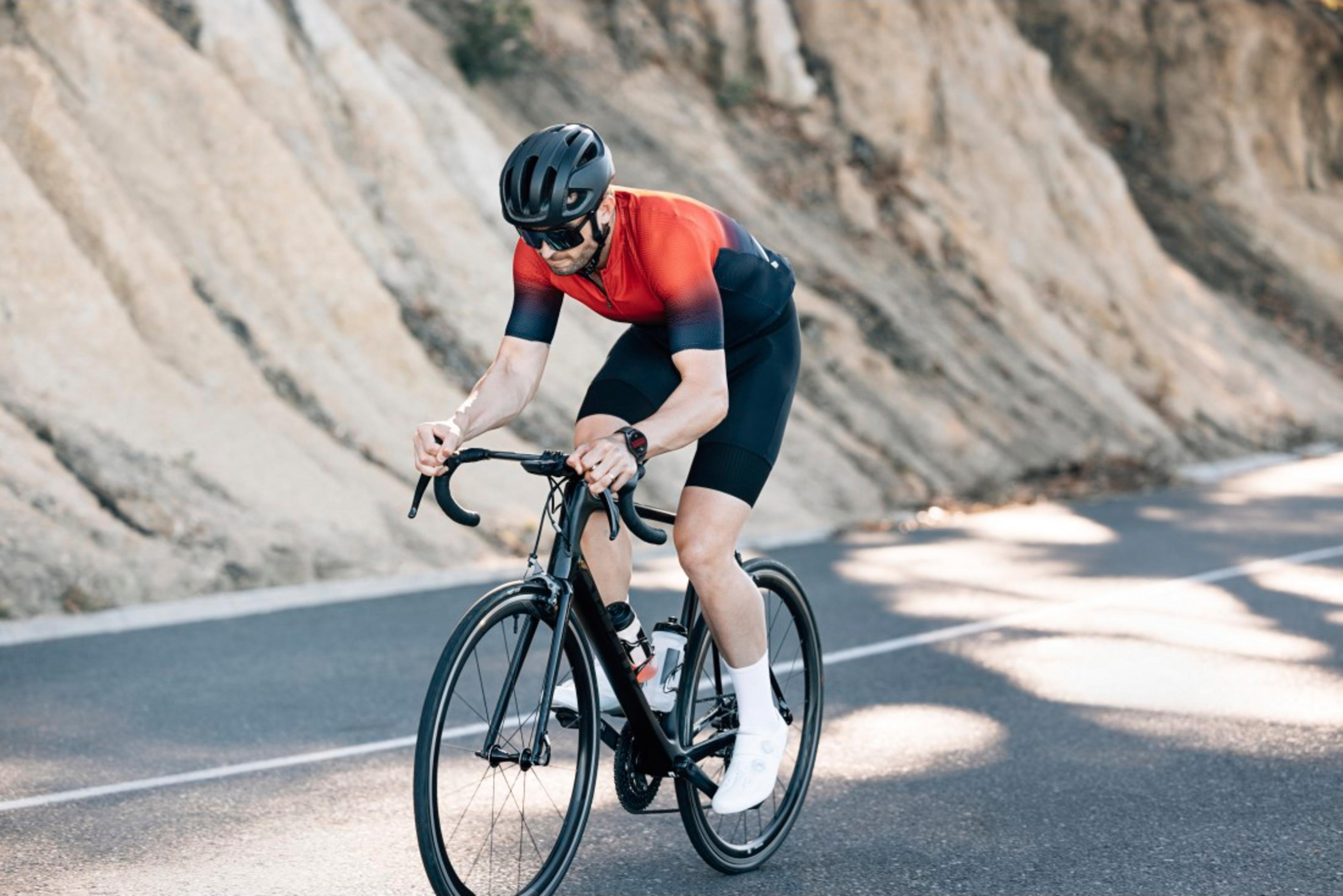 Un cycliste en tenue rouge roule à vélo sur une route asphaltée extérieure.
