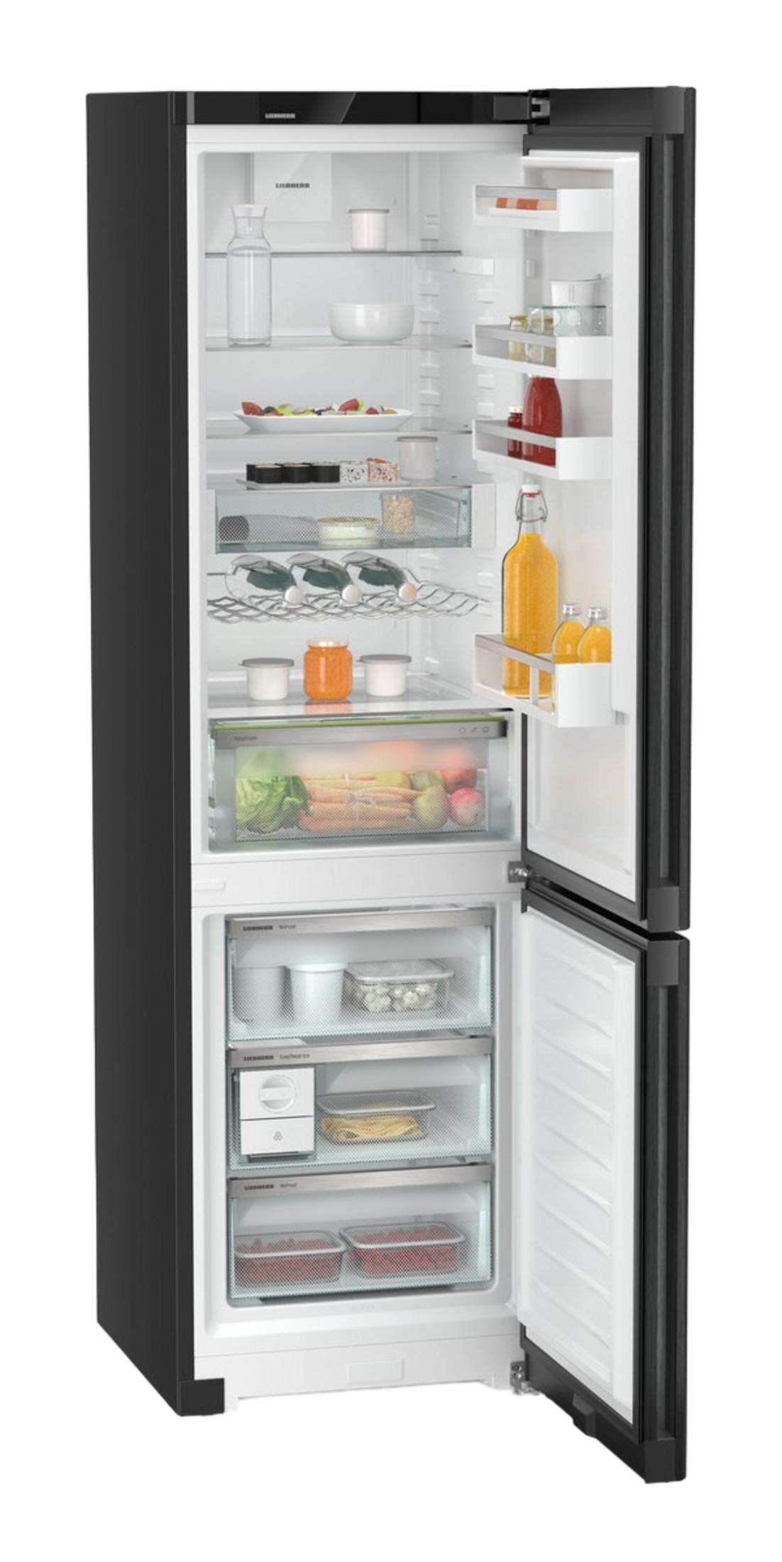 Refrigerador negro abierto con alimentos como frutas, verduras y bebidas.