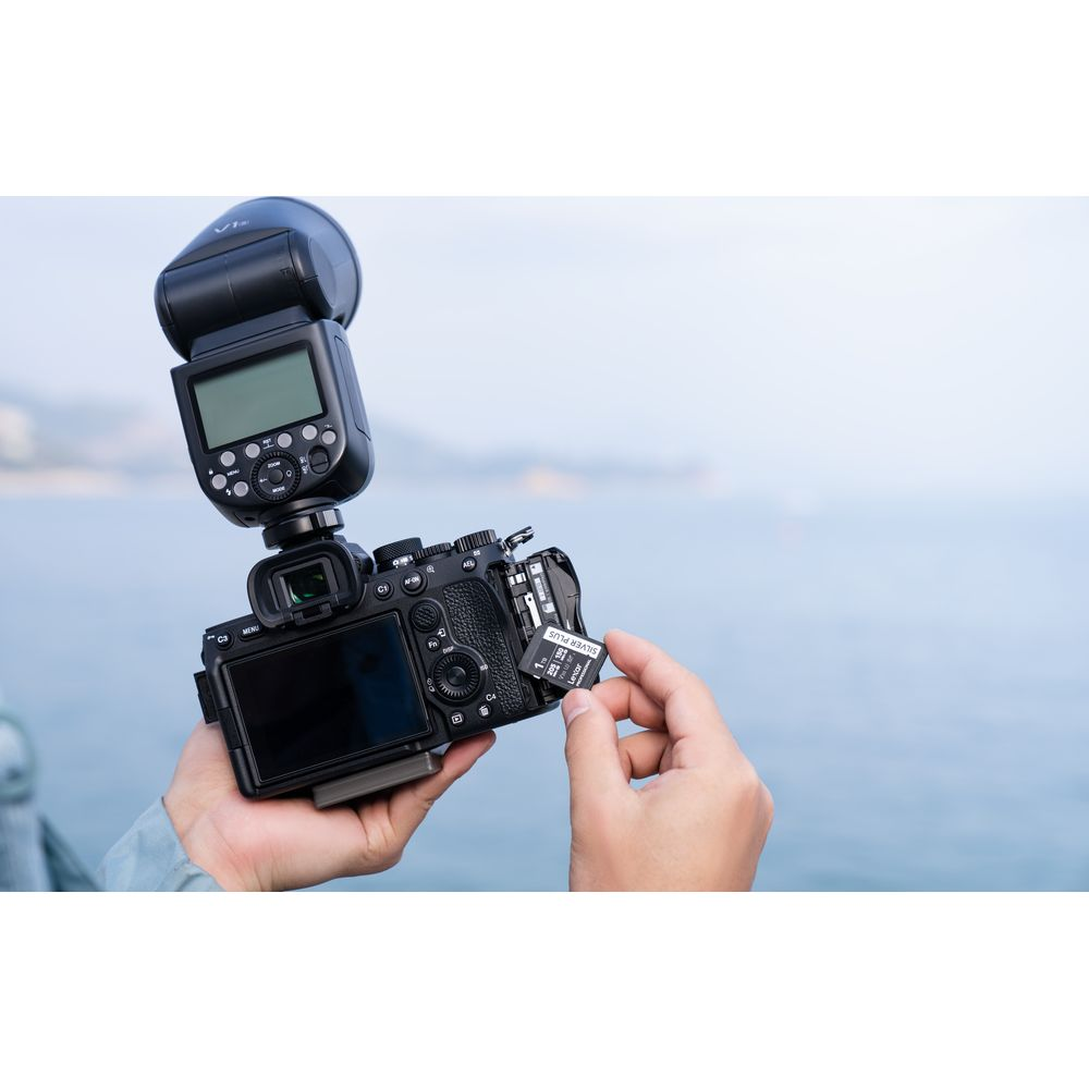 Una mano inserisce una scheda di memoria in una fotocamera con flash.