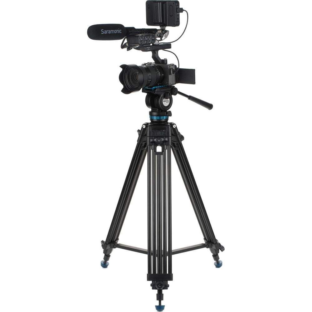 Een camera met microfoon en batterij op een zwart statief.