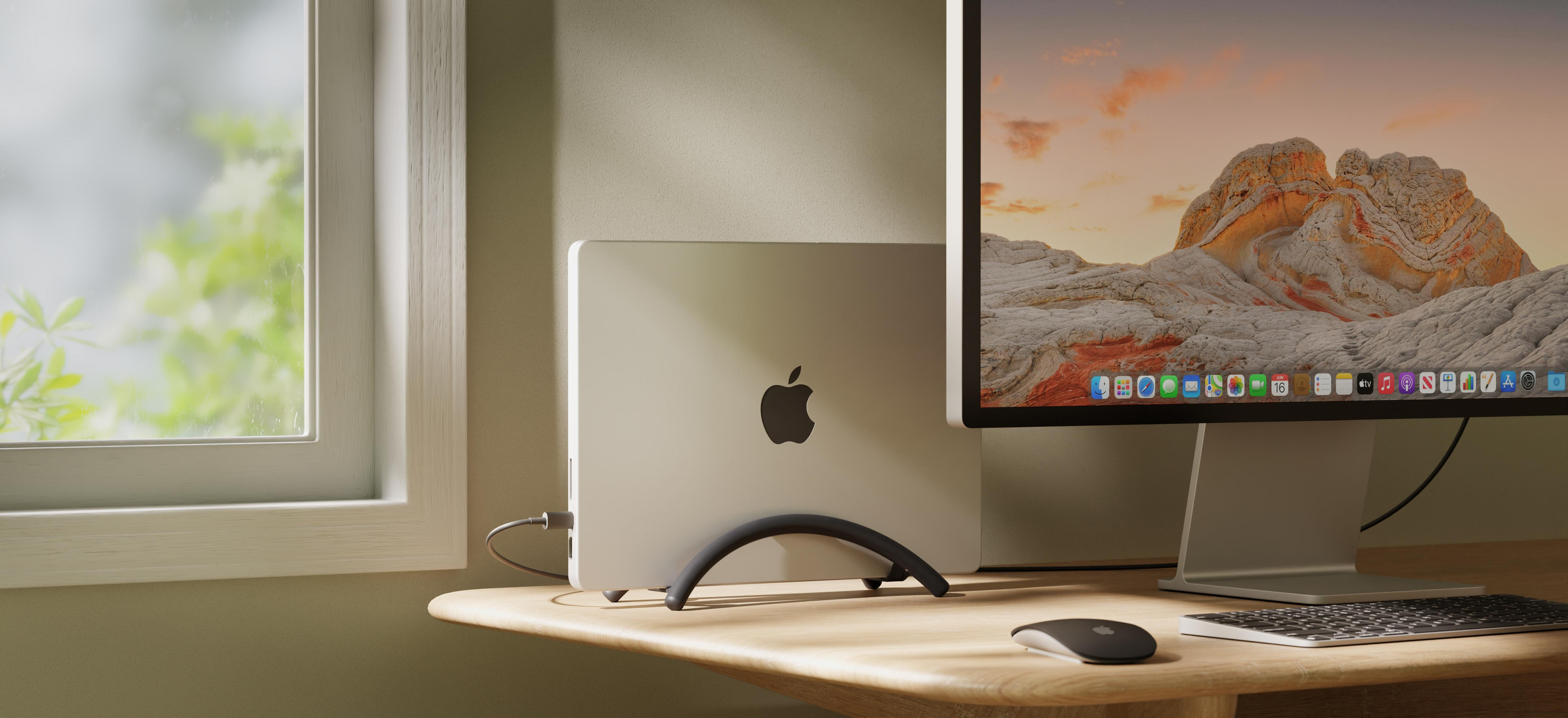 Laptop e monitor Apple su scrivania in legno, finestra con verde sullo sfondo.