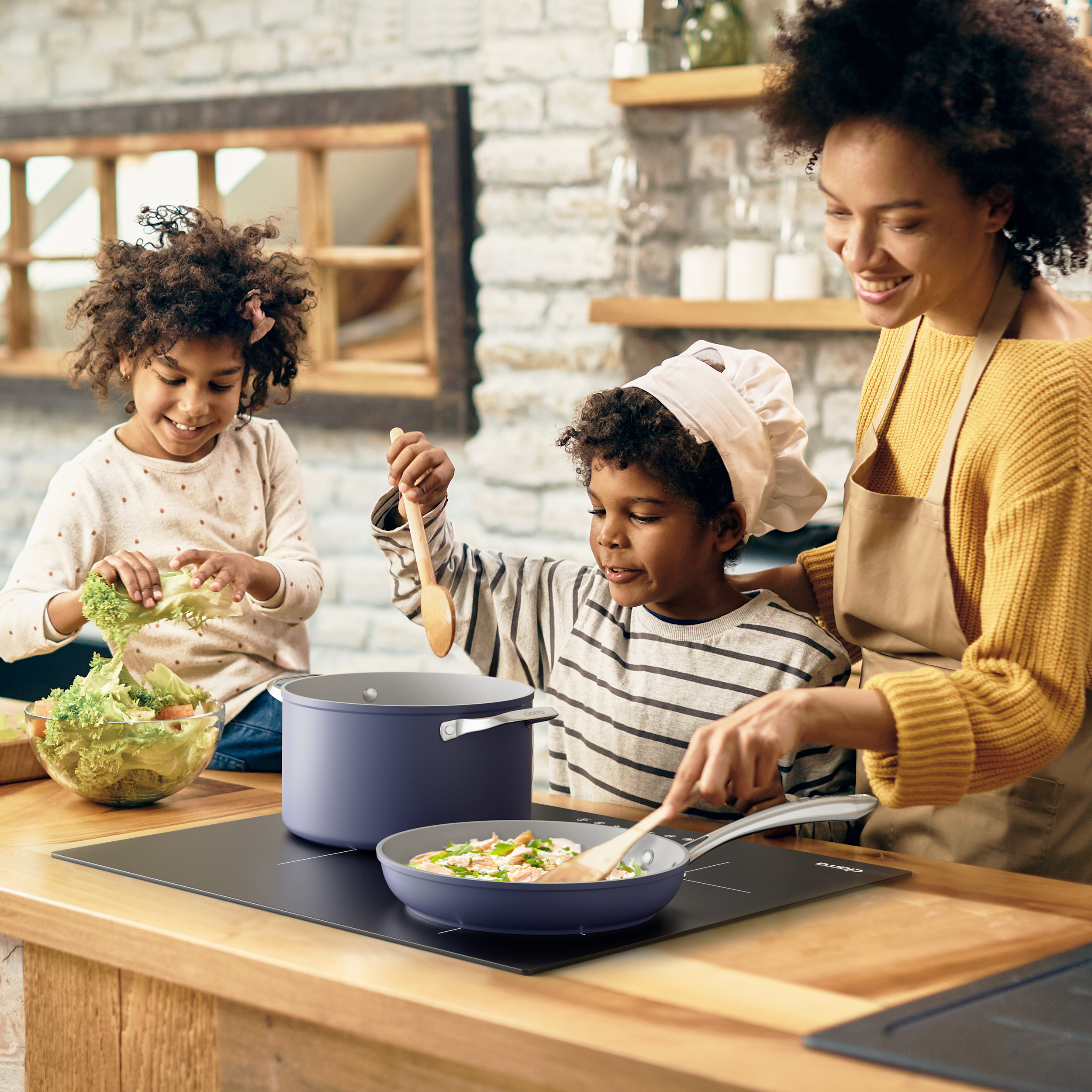 Mère et enfants cuisinent ensemble dans une cuisine. Un garçon remue des aliments dans une poêle.