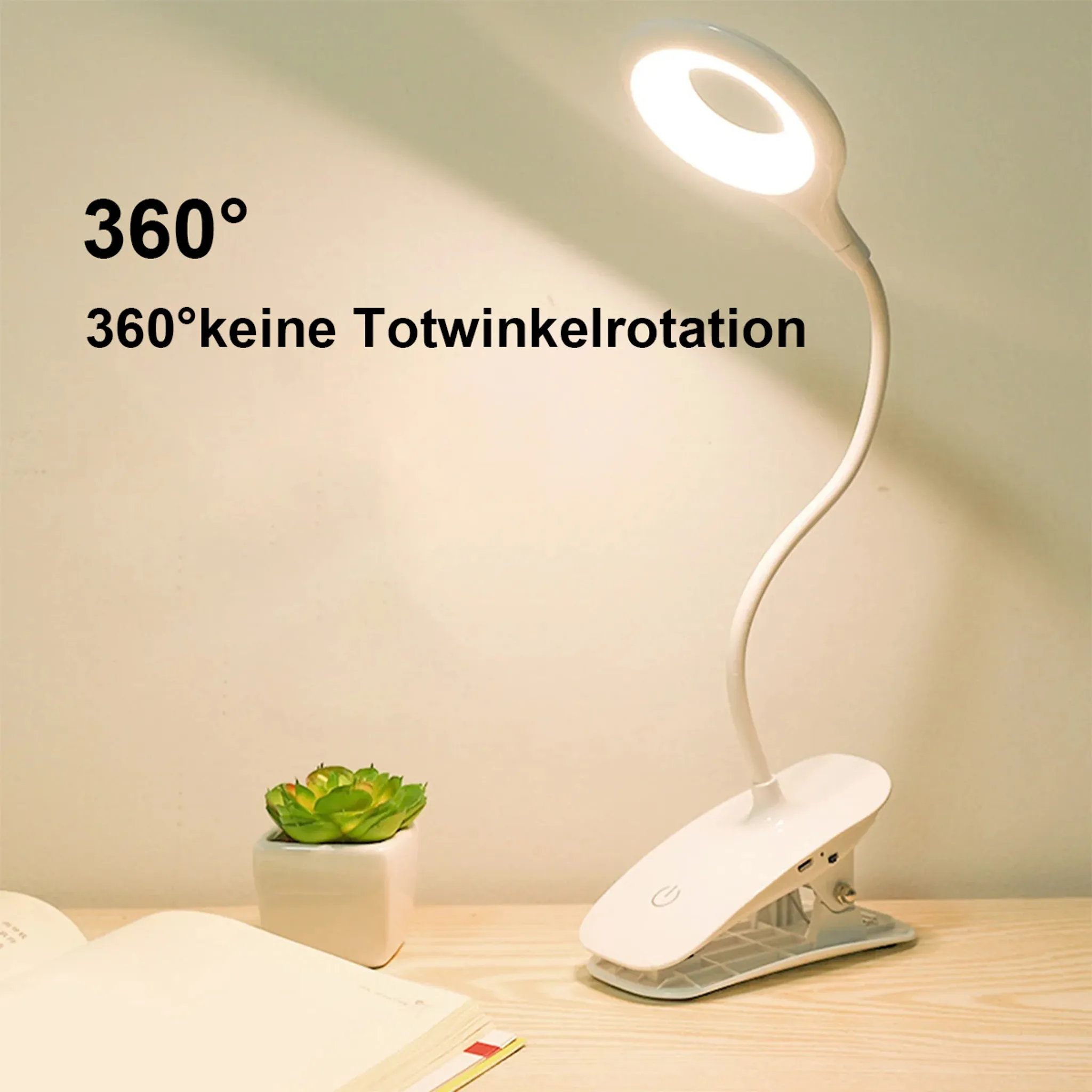 Eine weiße Klemmlampe mit LED-Ringlicht leuchtet auf einem Schreibtisch.