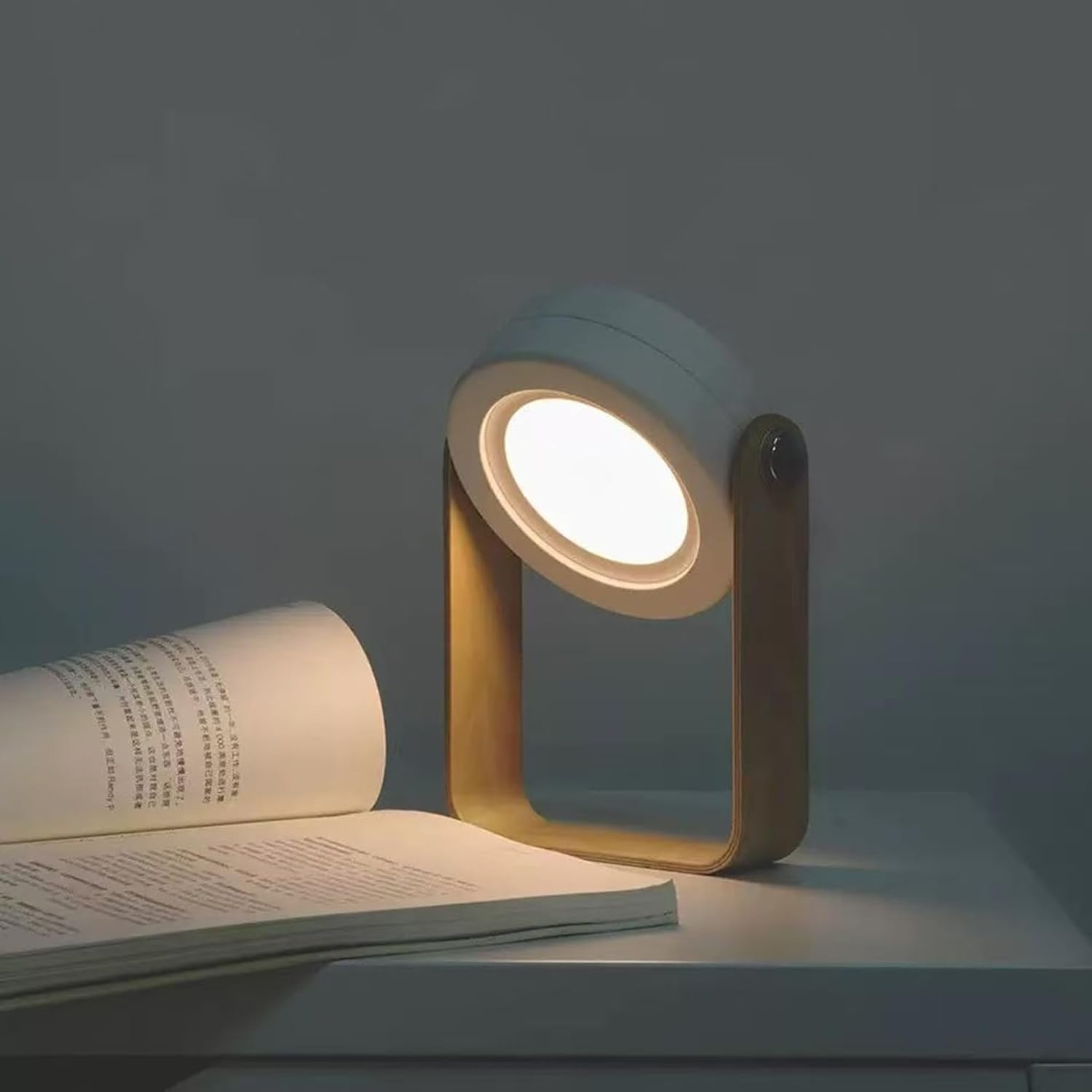 Eine moderne Nachttischlampe mit Holzrahmen beleuchtet ein aufgeschlagenes Buch.