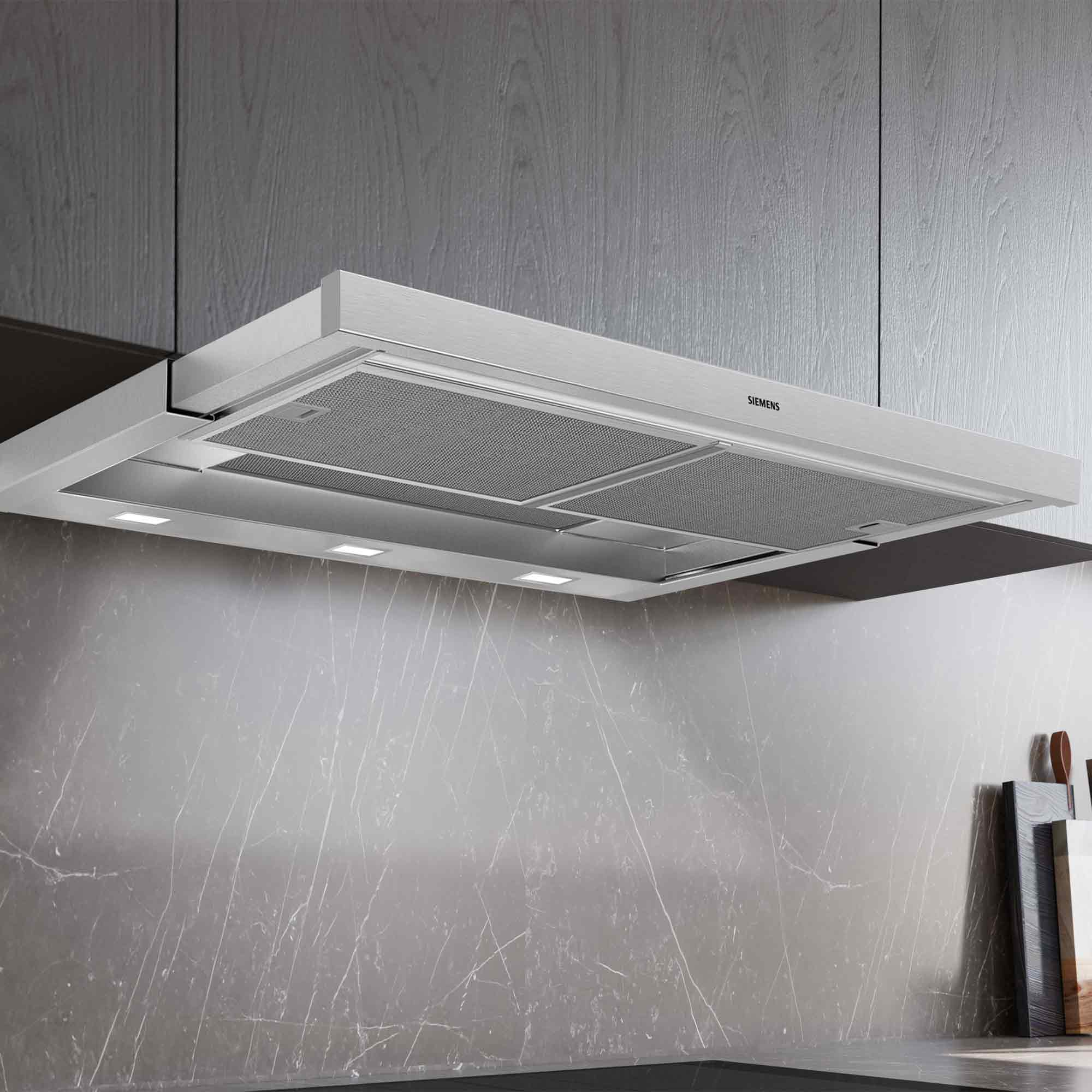 Eine moderne Edelstahl-Dunstabzugshaube über einem Marmor-Backsplash.