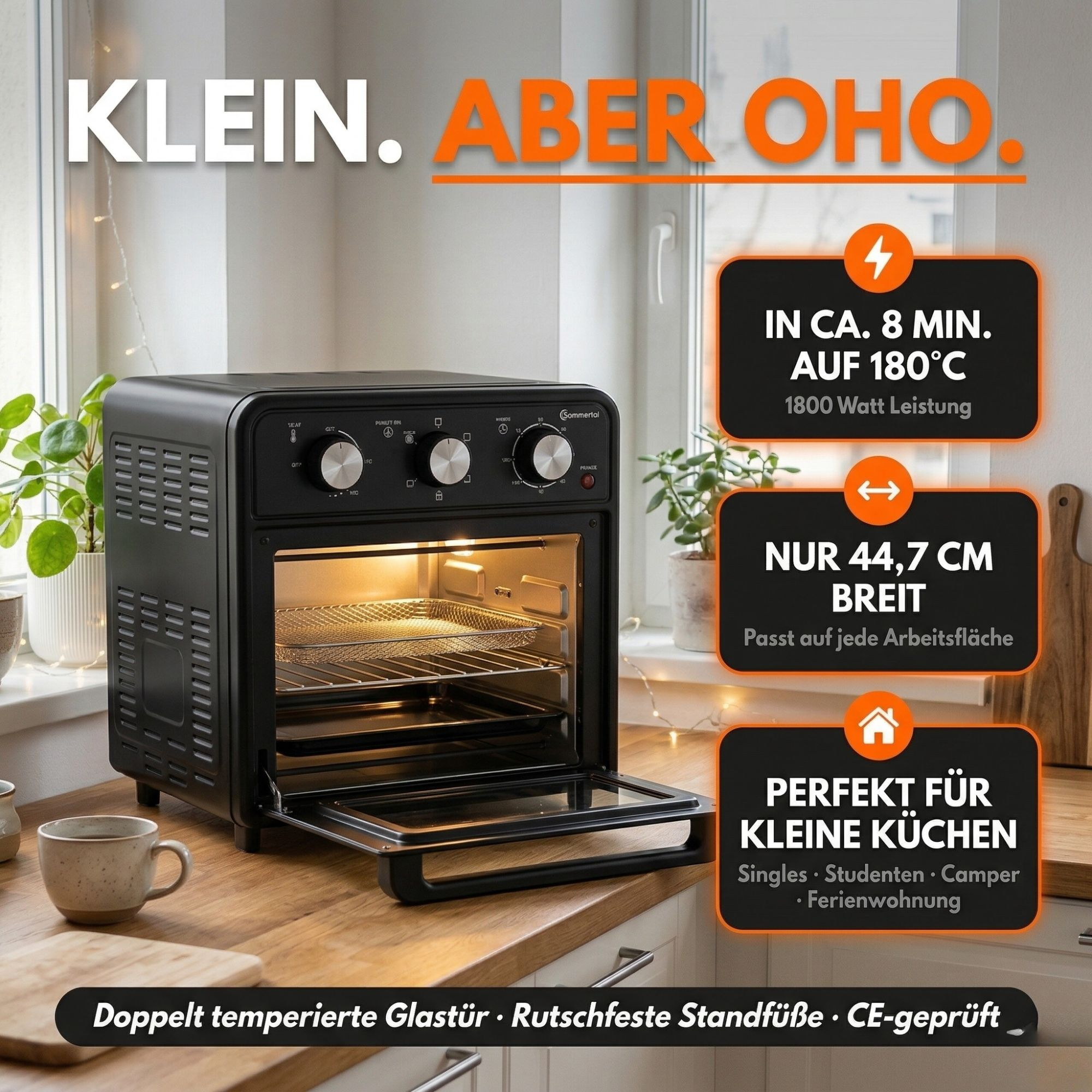 Kompakter schwarzer Backofen mit Zubehör auf einer Arbeitsplatte.