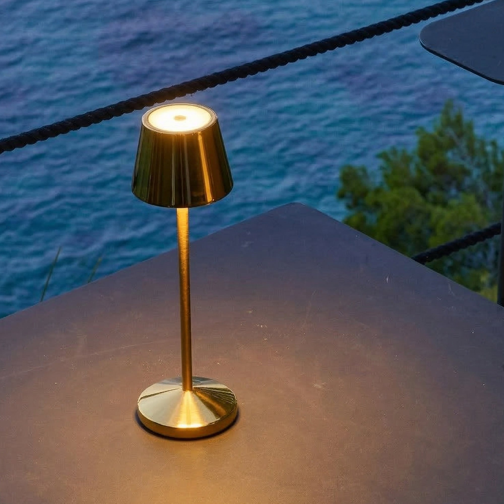 Eine goldene Tischlampe steht auf einem Tisch mit Blick auf das Meer.