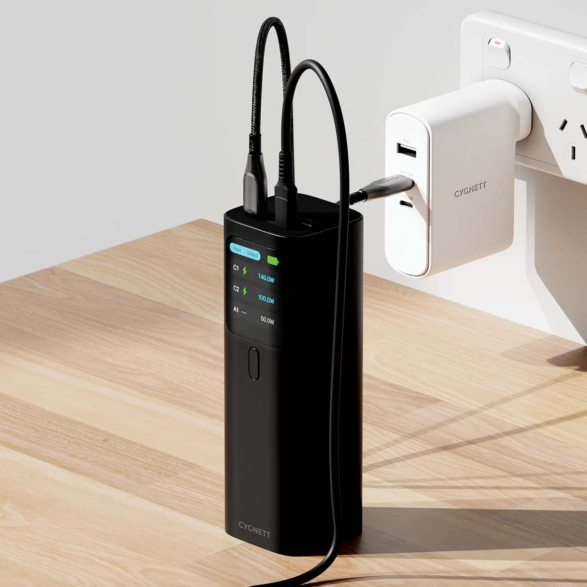 Une batterie externe noire avec des câbles connectés à une prise murale blanche.