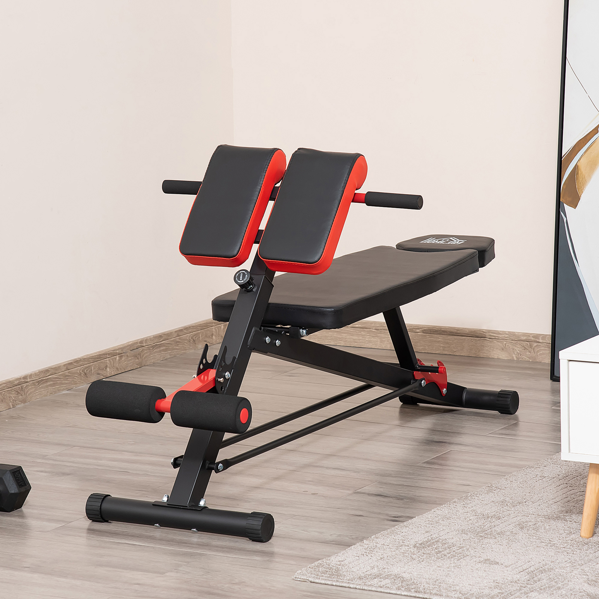 Ein schwarzes und rotes Trainingsgerät mit Polstern und Beinstützen auf Holzboden.