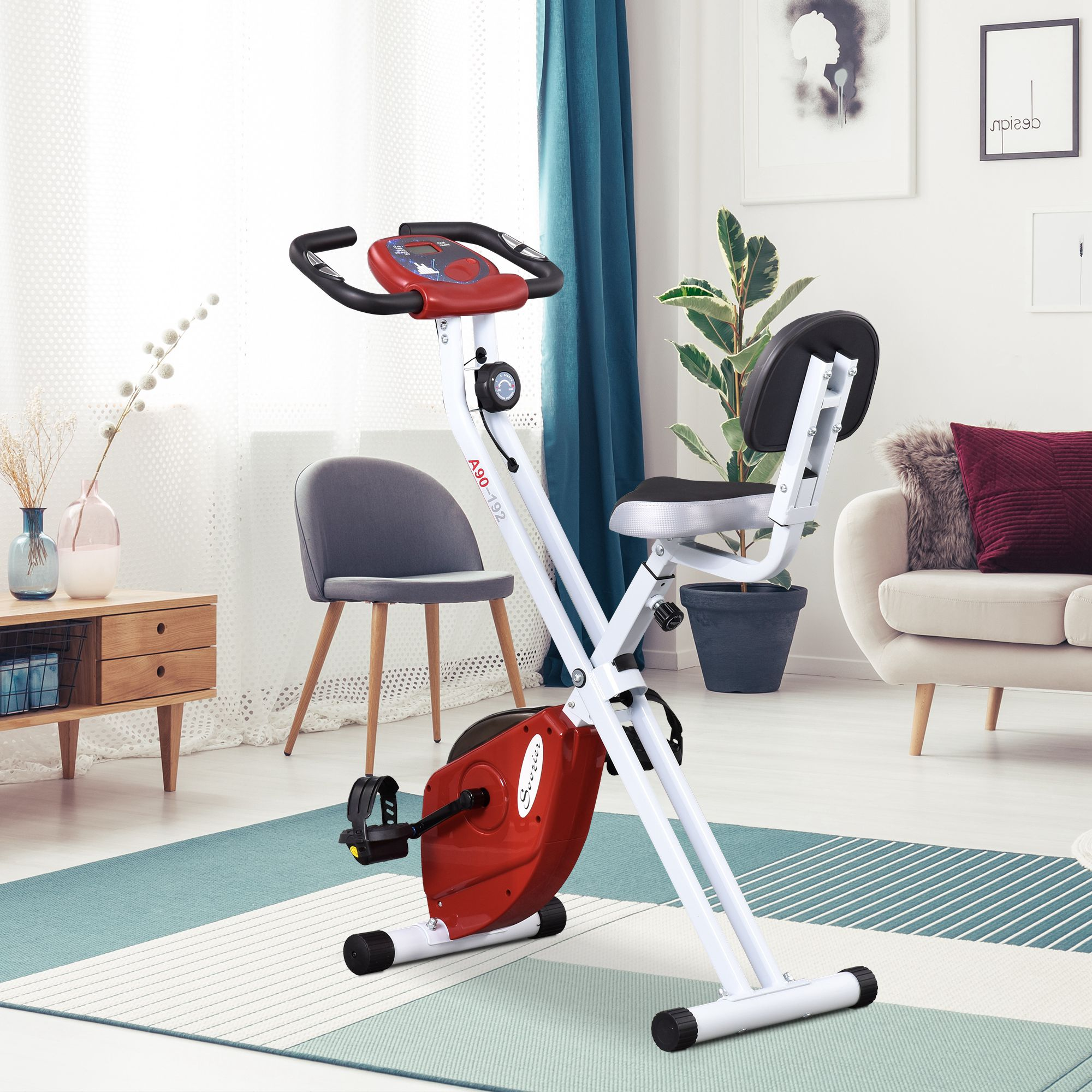 Ein rot-weißer Heimtrainer steht in einem hellen Wohnzimmer mit Teppich.