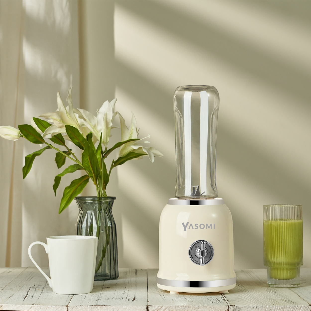 Krem rengi blender, cam hazne, fincan, çiçekli vazo ve meyve suyu bardağı bulunur.
