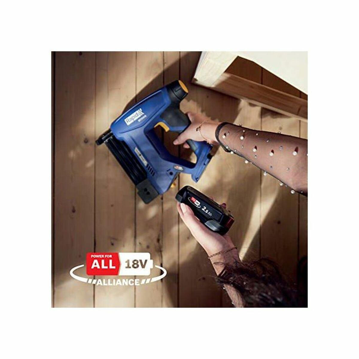 Una mano tiene una sparachiodi blu e gialla, un'altra una batteria da 18V.