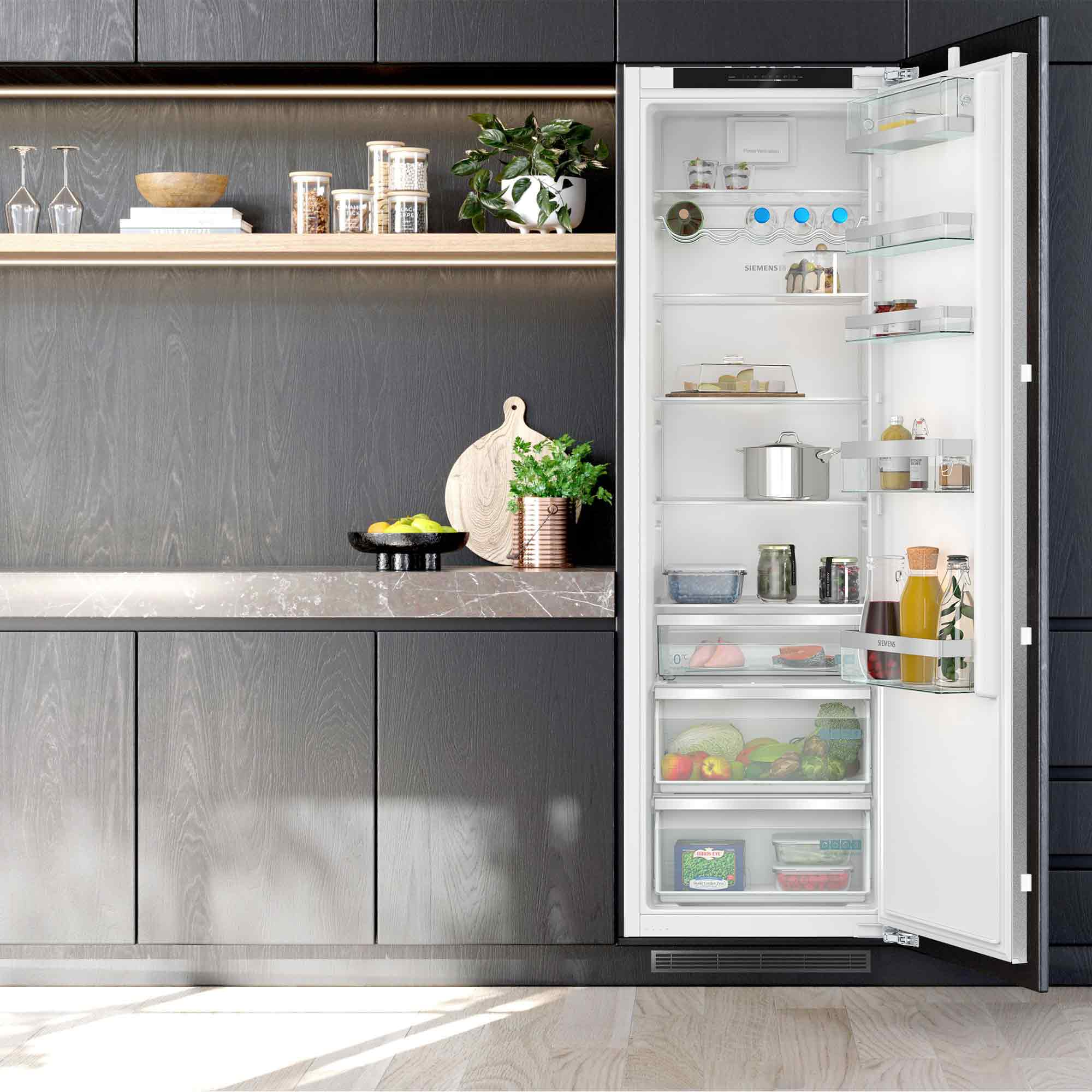 Offener Kühlschrank mit Lebensmitteln und Küchenschränken daneben.