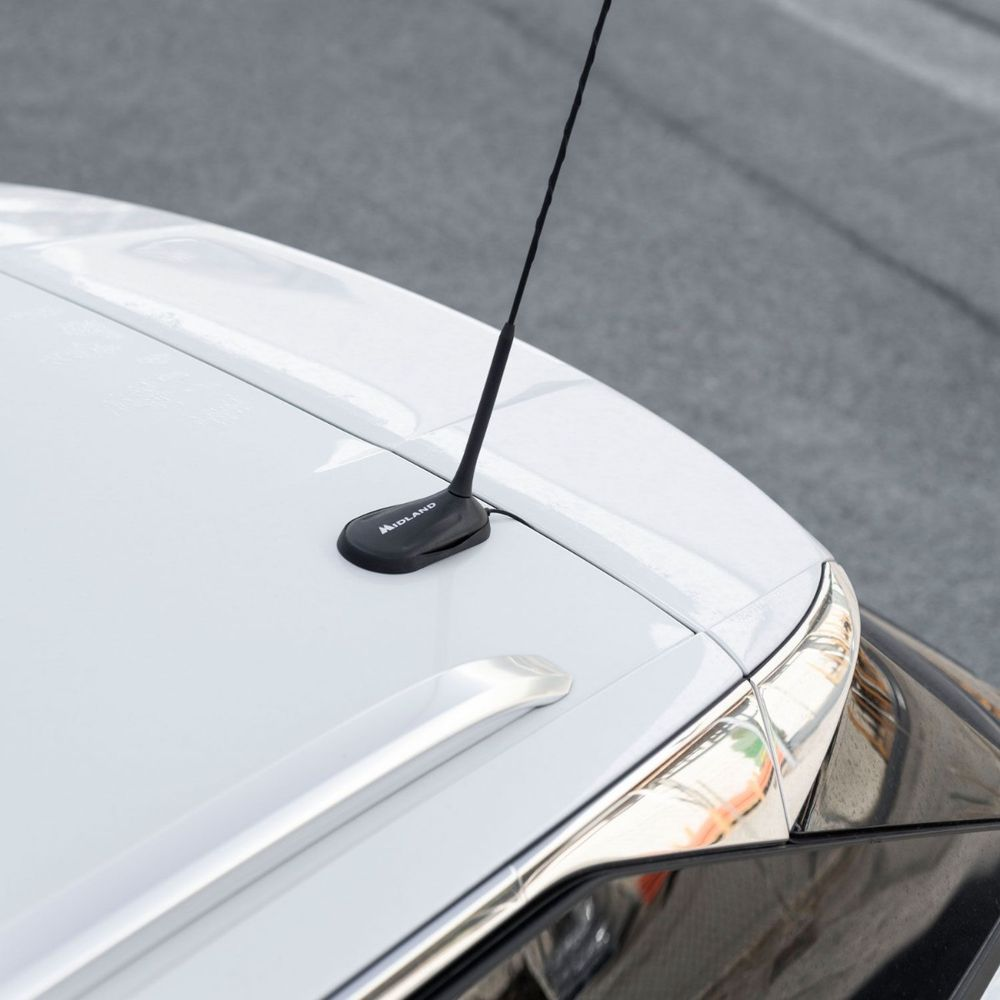 Eine schwarze Antenne mit der Aufschrift "MIDLAND" auf dem Dach eines weißen Autos.