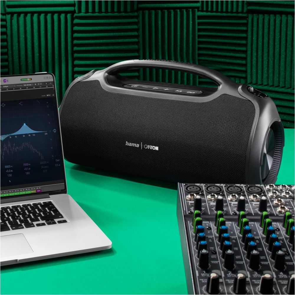 Altoparlante Bluetooth nero con laptop e mixer su tavolo verde.
