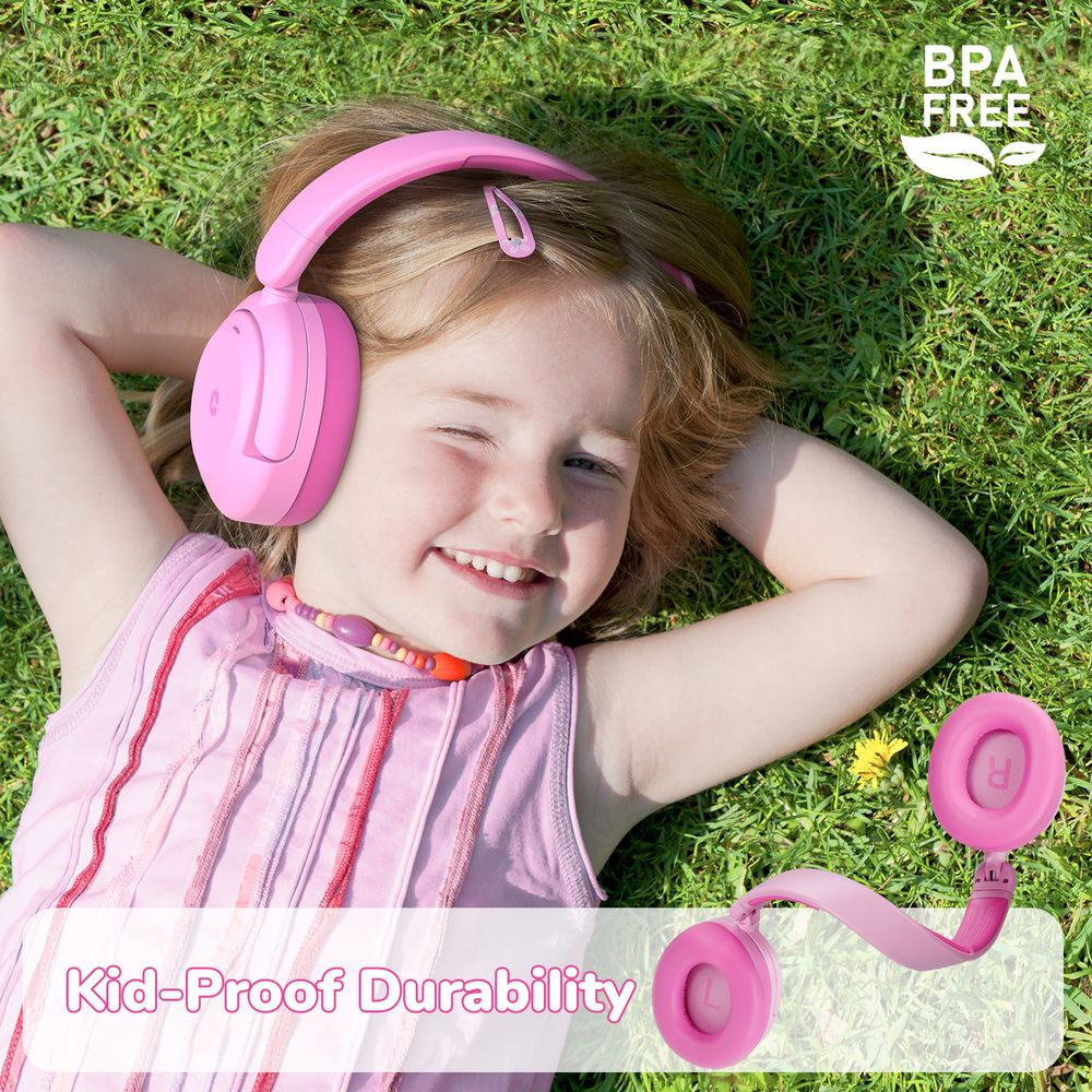 Une fille souriante portant un casque rose est allongée dans l'herbe.