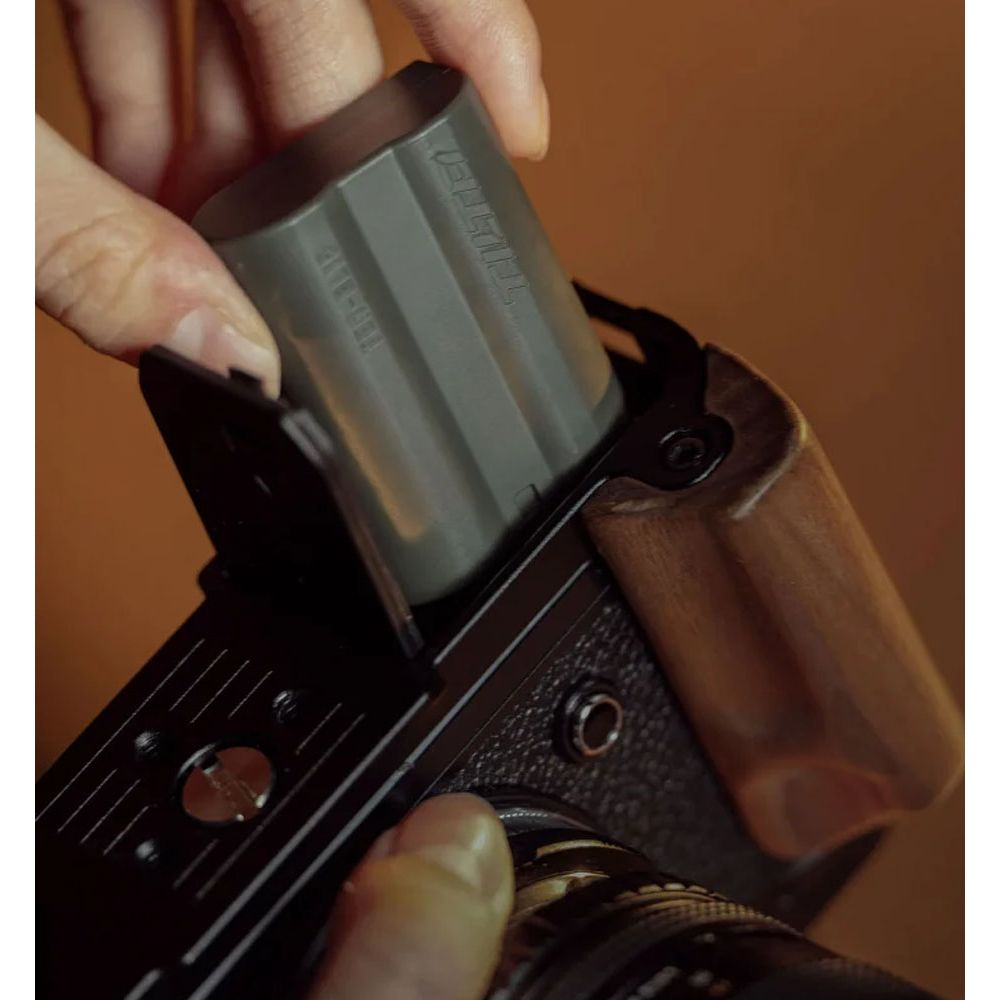 Una mano inserisce una batteria grigia in una fotocamera.