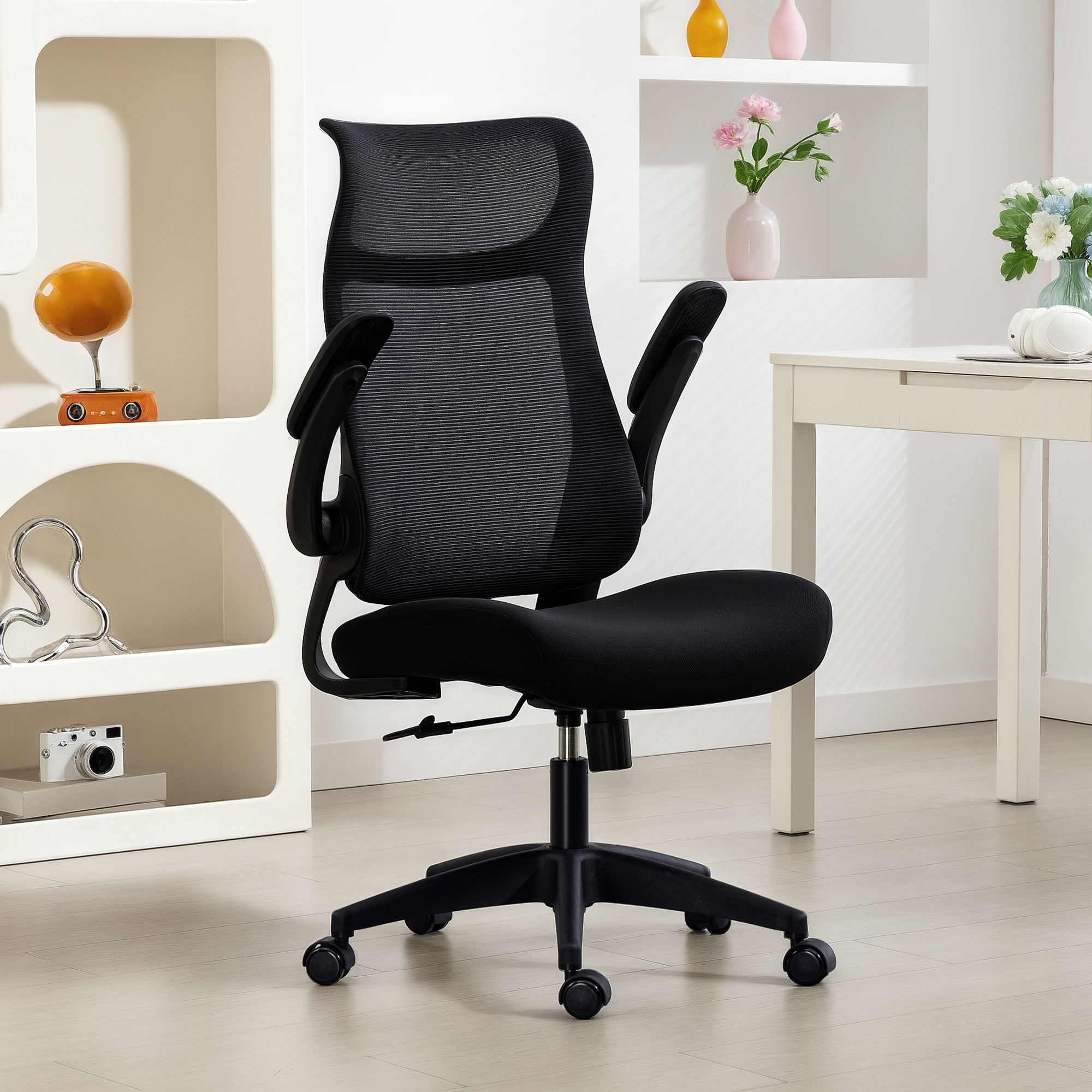Ein schwarzer Netzstuhl steht vor einem Schreibtisch mit Blumenvasen und Dekorationen.