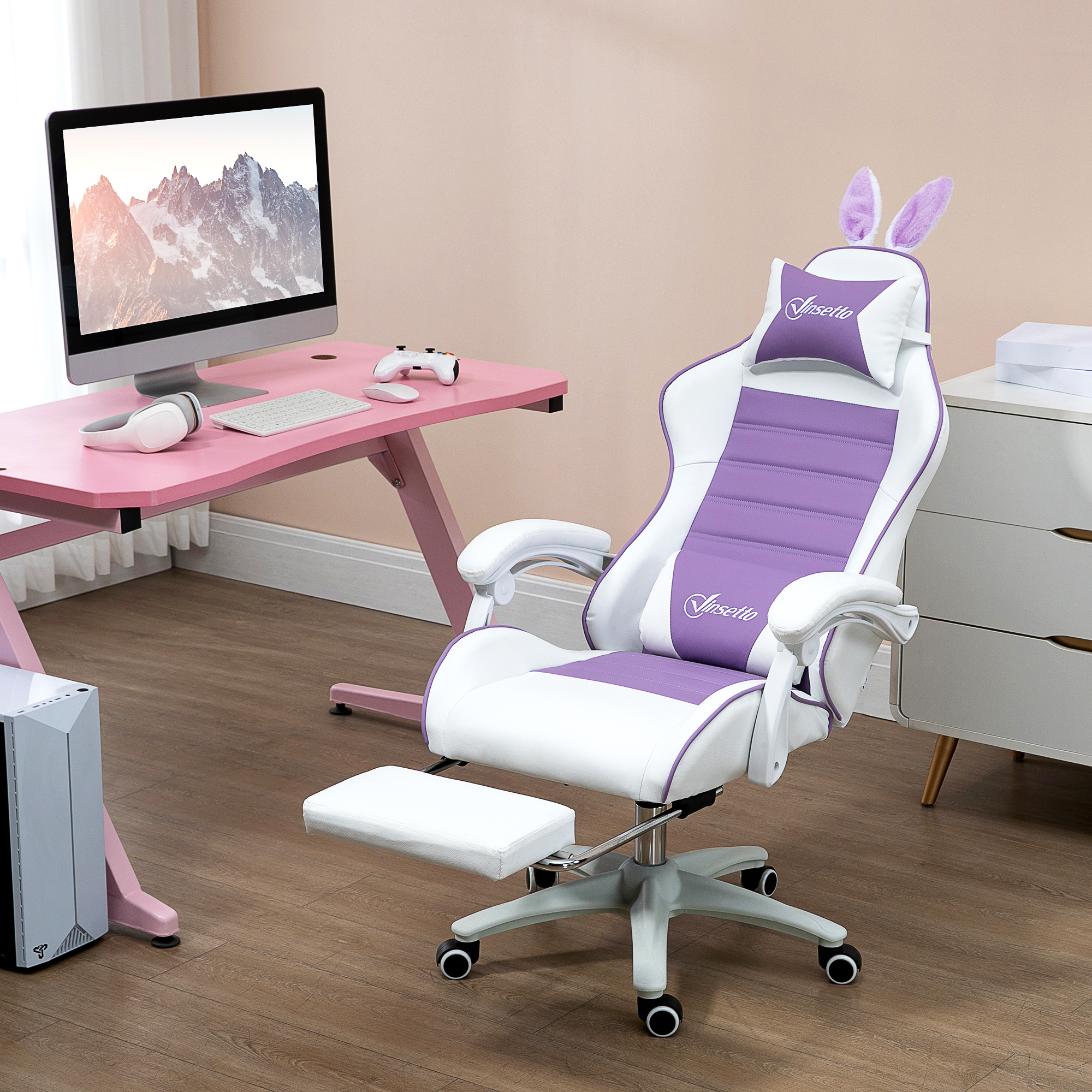 Ein weißer und lila Gaming-Stuhl mit Hasenohren steht neben einem rosa Schreibtisch mit Computer.