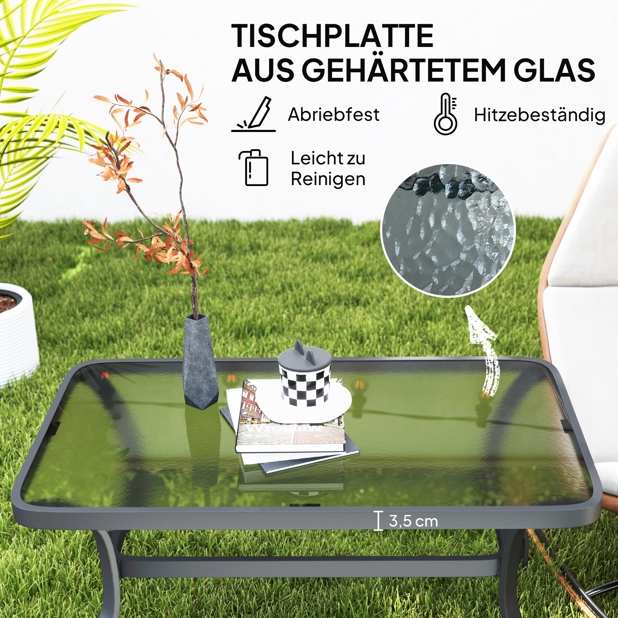 Ein grüner Glas-Gartentisch mit Büchern und einer Zuckerdose darauf.