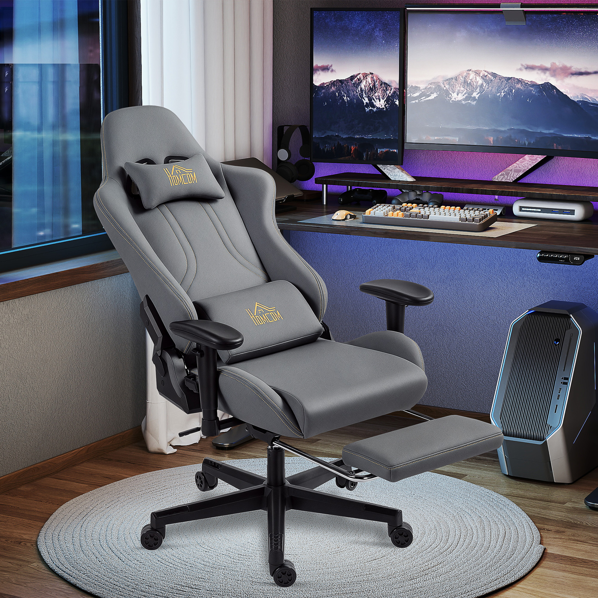 Grauer Gaming-Stuhl mit ausklappbarer Fußstütze vor einem Schreibtisch mit Monitoren.
