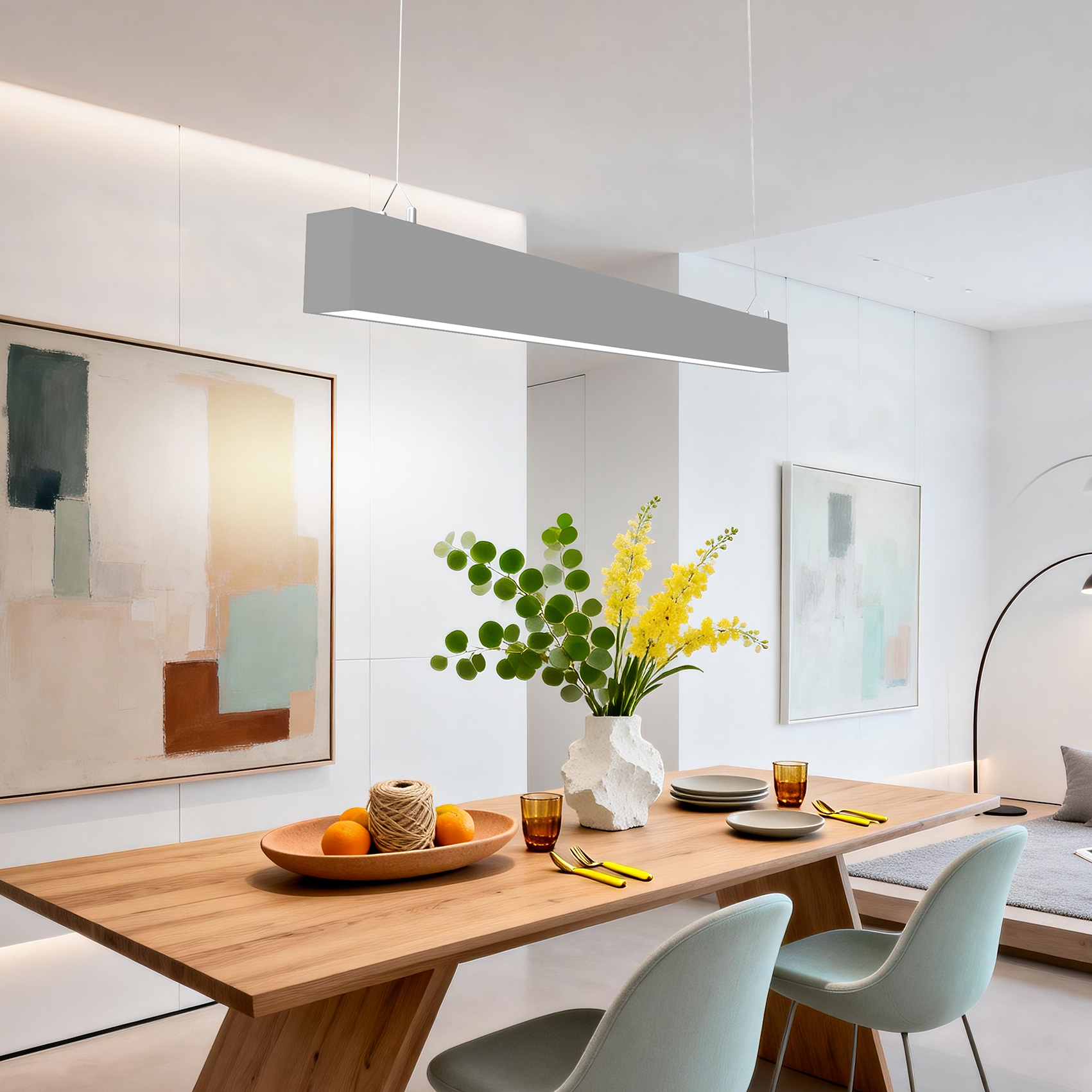 Una mesa de madera con naranjas, flores y platos en un comedor moderno.