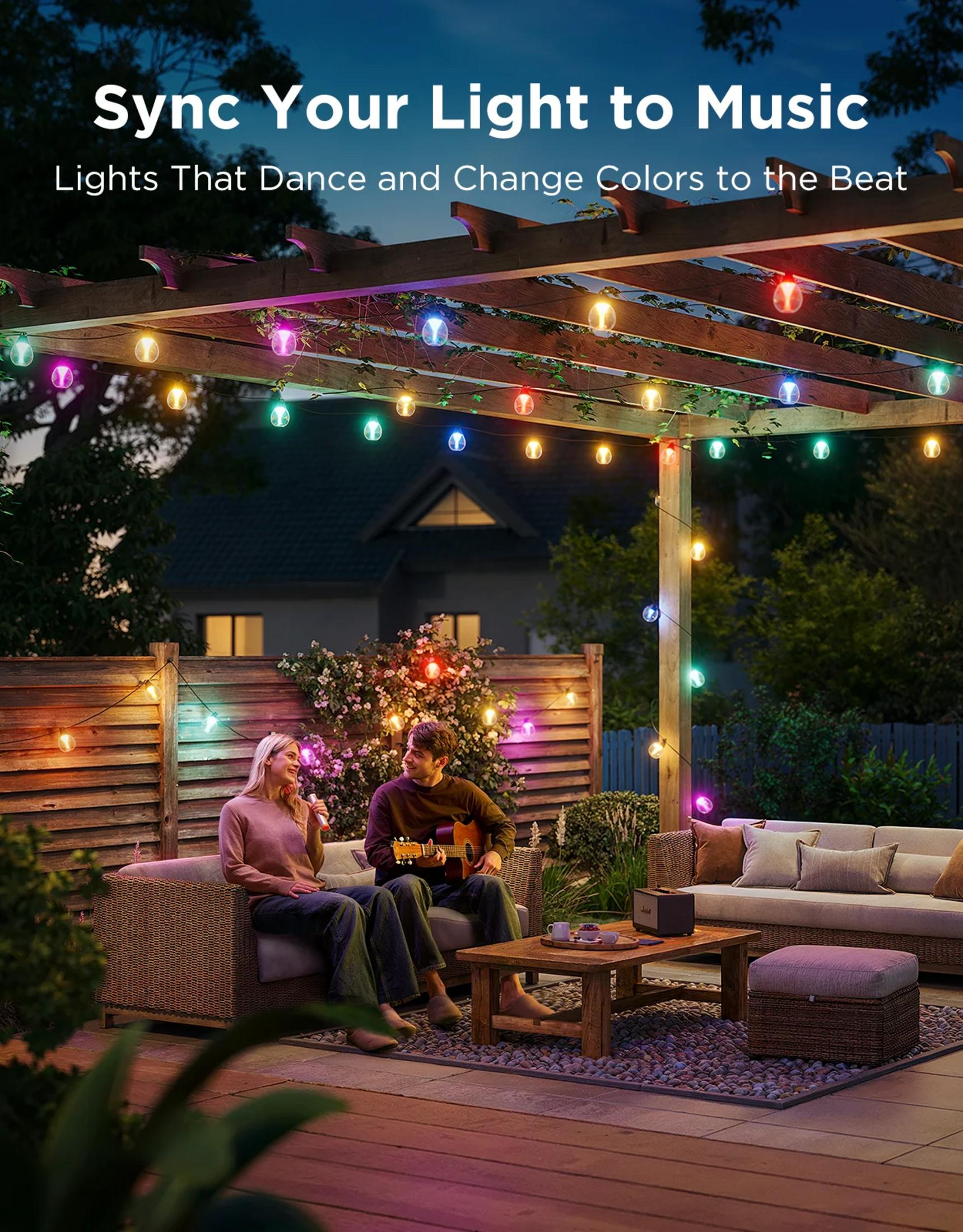 Paar auf einer Terrasse bei Nacht, beleuchtet von bunten Lichterketten.