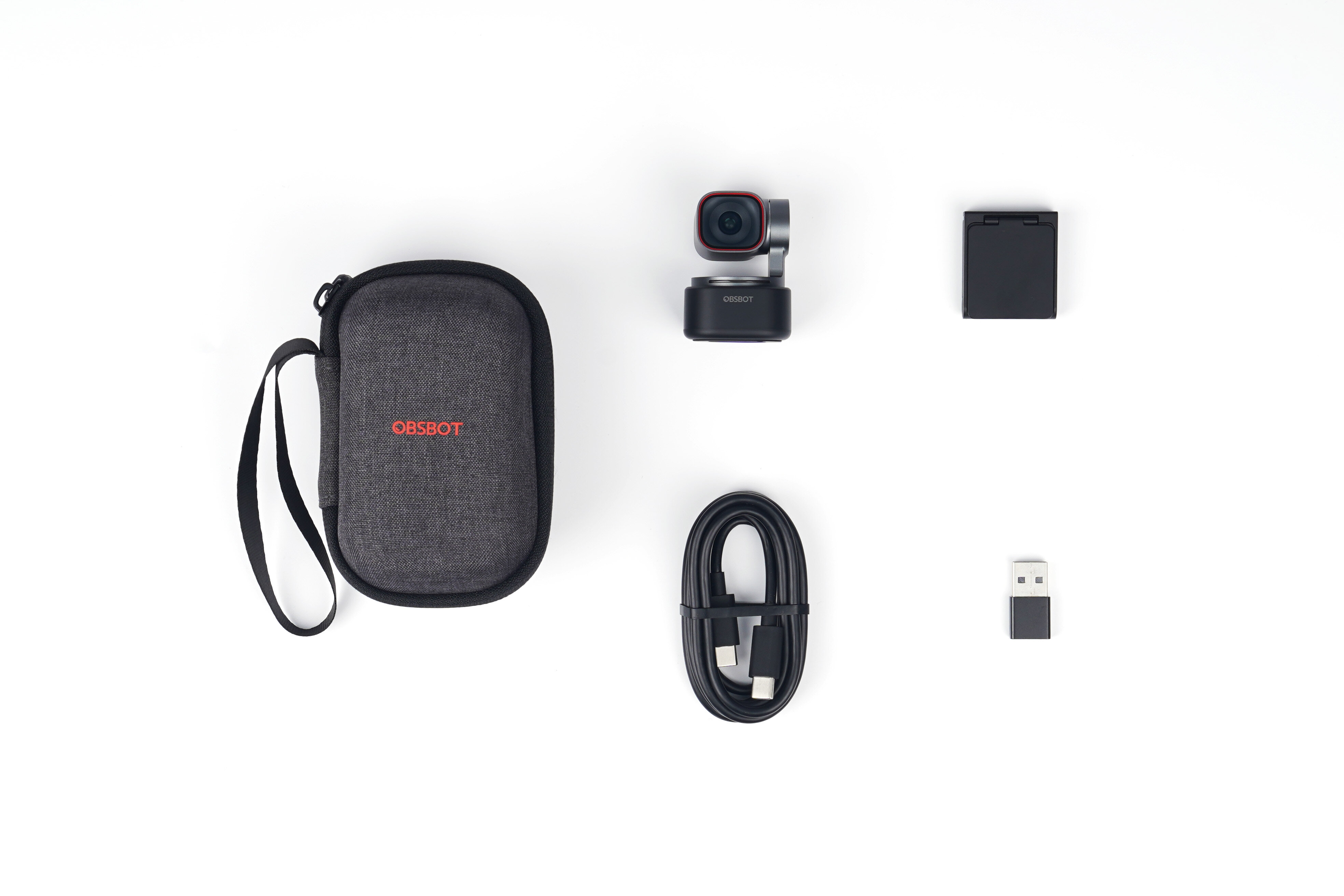 Graue Tasche, Kamera, Kabel und USB-Adapter auf weißem Hintergrund.