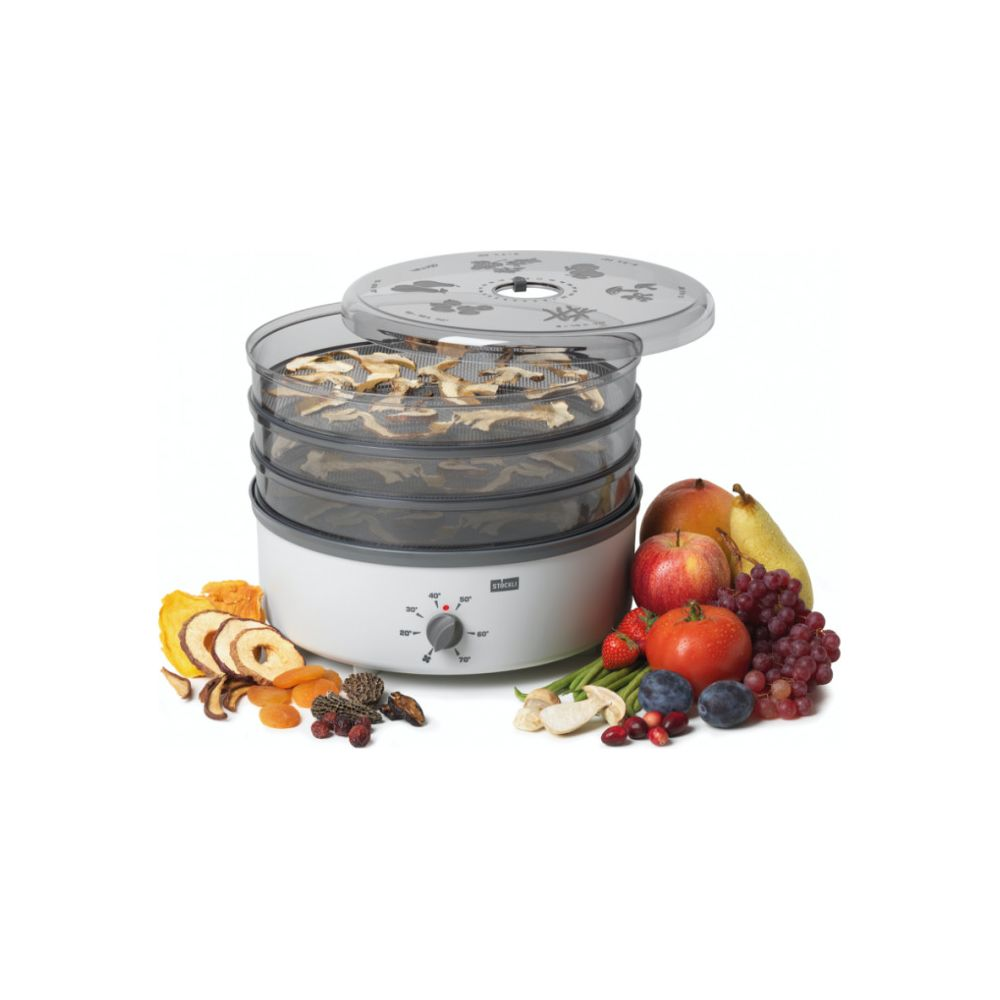 Un déshydrateur alimentaire à plusieurs niveaux rempli de fruits secs et de champignons, avec des fruits frais à côté.