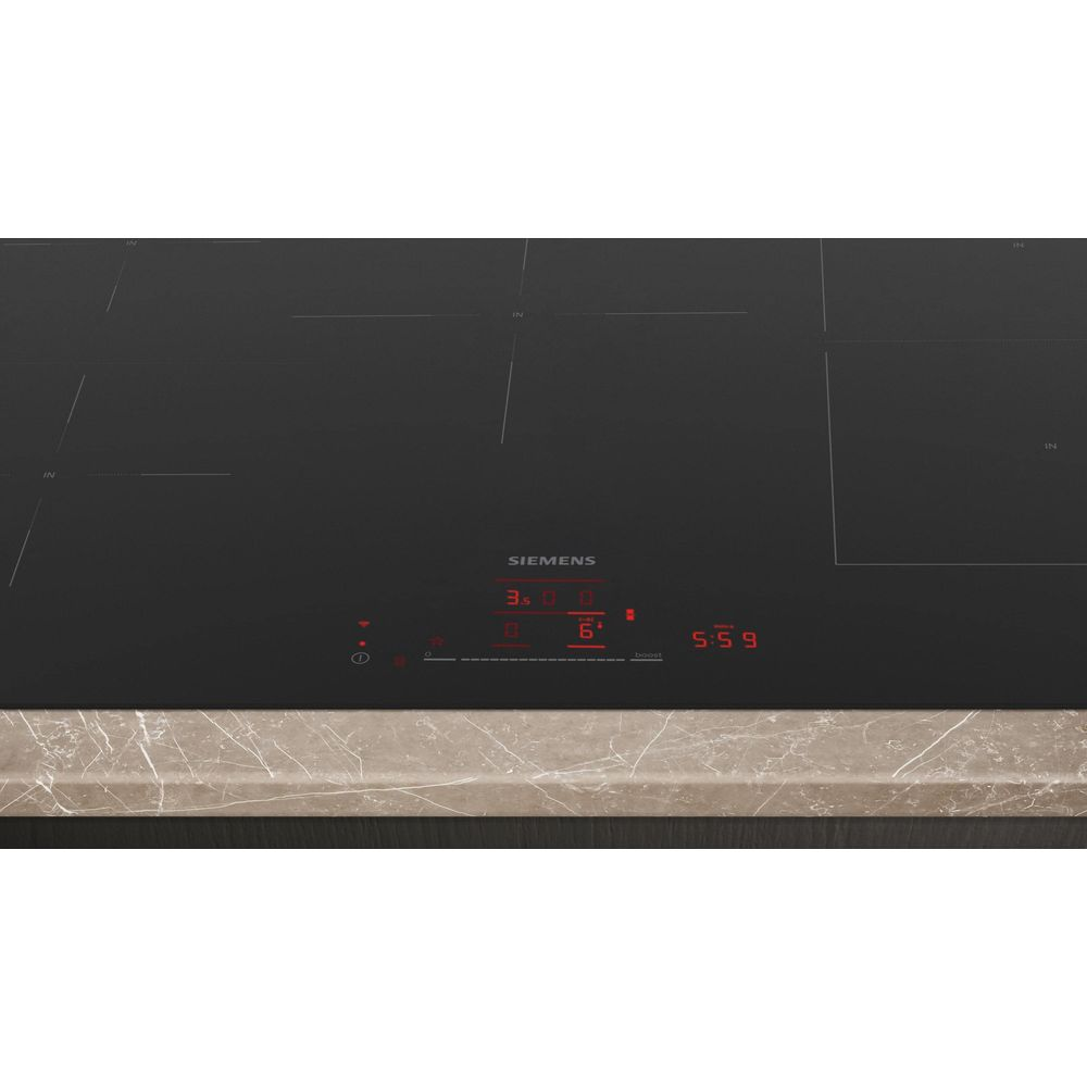 Plaque à induction Siemens noire avec écran numérique rouge et plan de travail marbre.