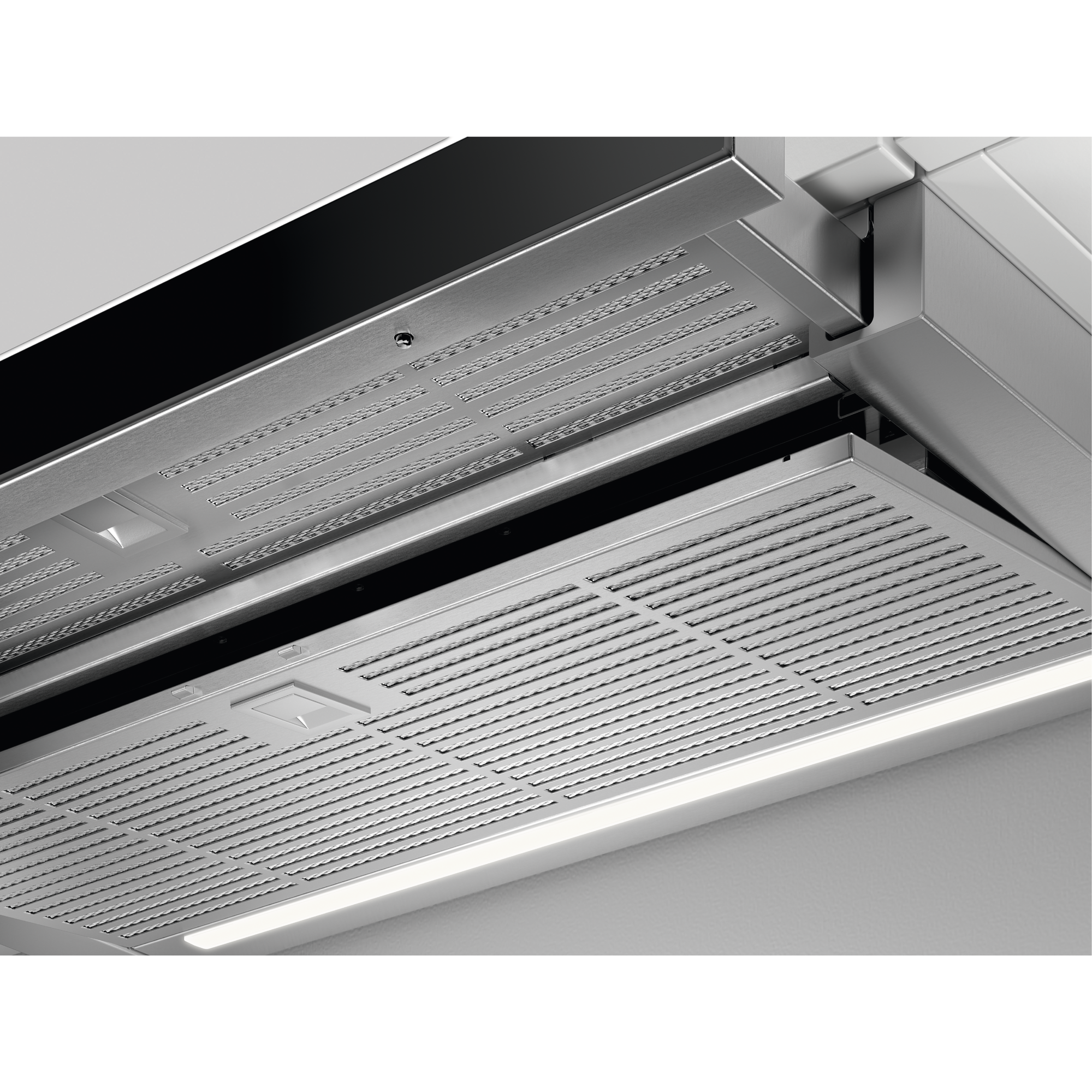 Primo piano di una cappa da cucina con filtri metallici e illuminazione integrata.