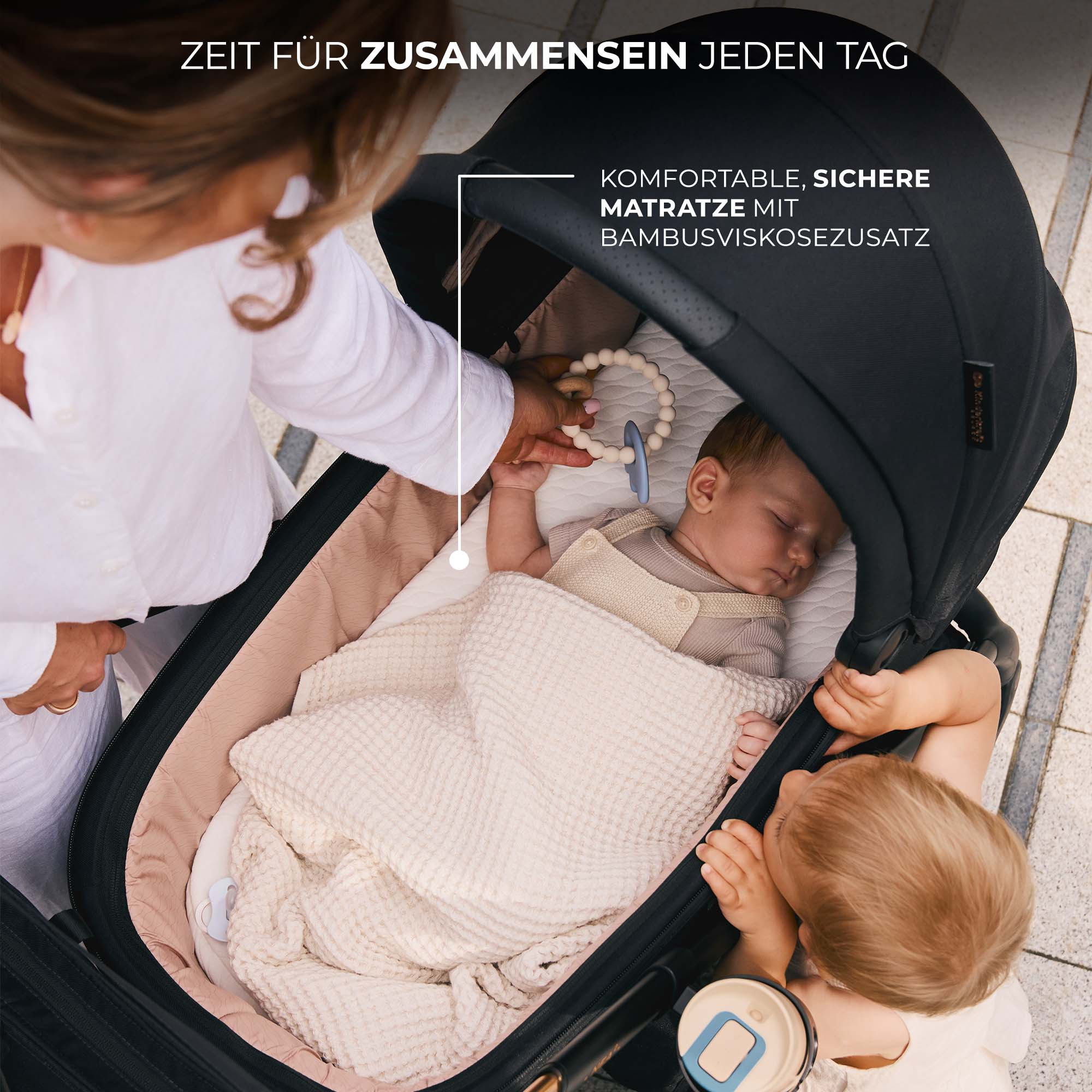 Frau schiebt Kinderwagen mit schlafendem Baby und Kleinkind daneben.